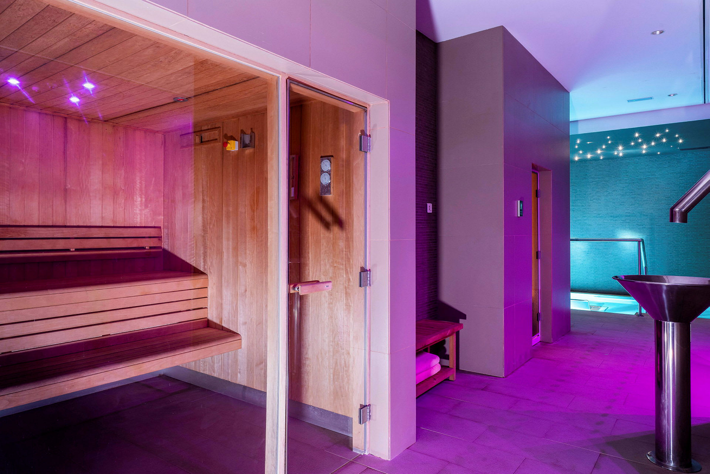 Spa, jossa on puupaneeleilla varustettu sauna, valaistu käytävä ja näkymä uima-altaalle. (Tekoälyn luoma teksti)