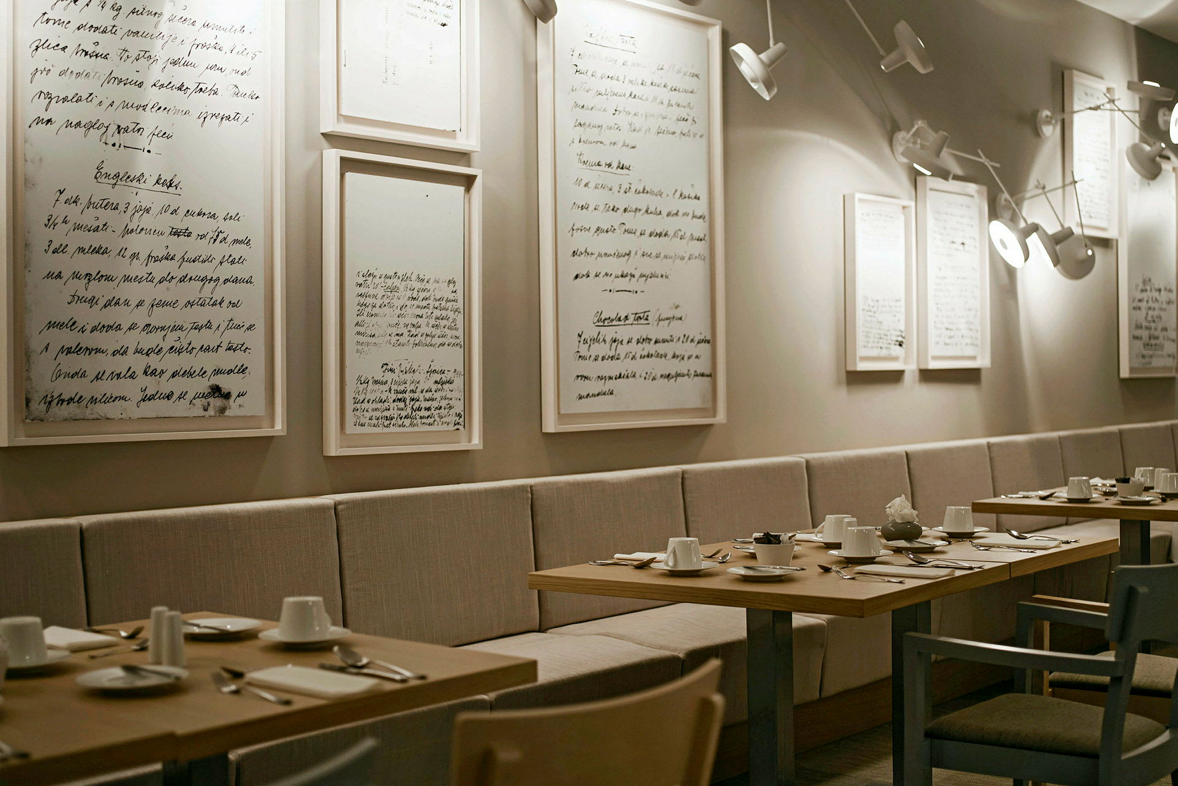 Tyylikäs ravintola, jossa on illalliseen katettuja pöytiä ja minimalistisia tauluja seinällä. (Tekoälyn luoma teksti)