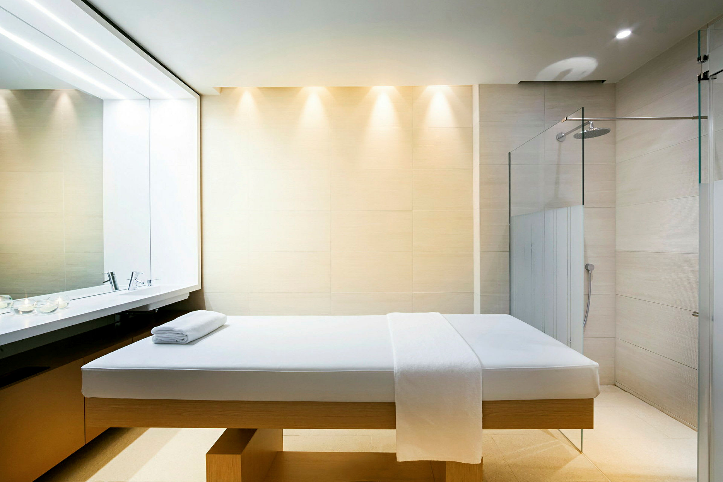 Spa-huone, jossa hierontapöytä, pyyhkeitä ja suihku taustalla. (Tekoälyn luoma teksti)