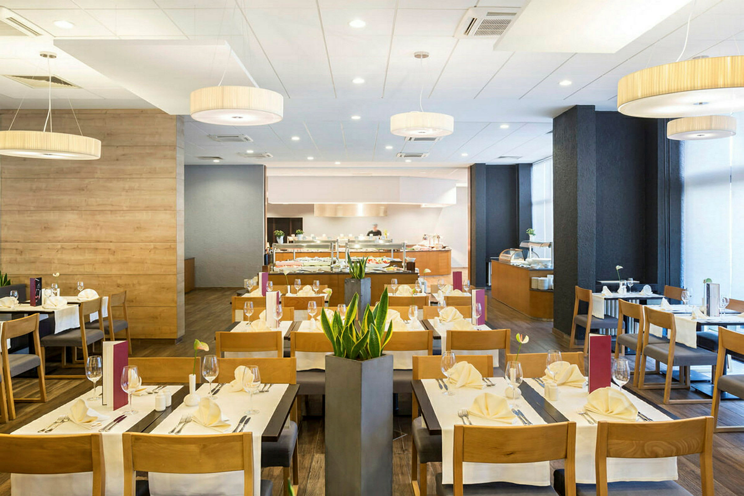 Ruokailutila, jossa katettuja pöytiä, tuoleja ja buffet taustalla. (Tekoälyn luoma teksti)