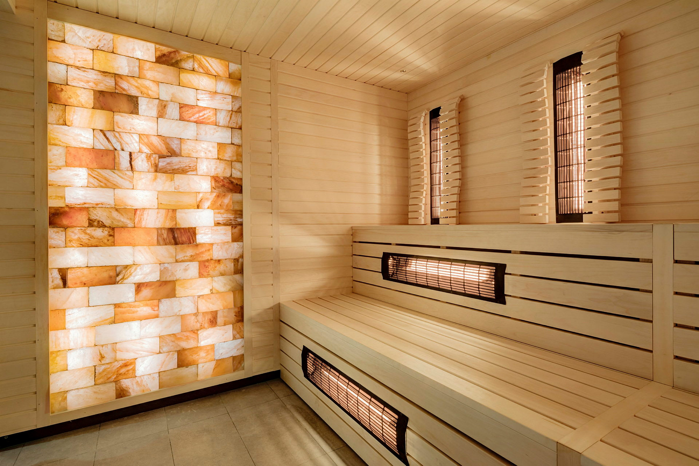 Sauna, jossa on puupaneelit ja seinä oransseista ja valkoisista suolakrystalleista. (Tekoälyn luoma teksti)