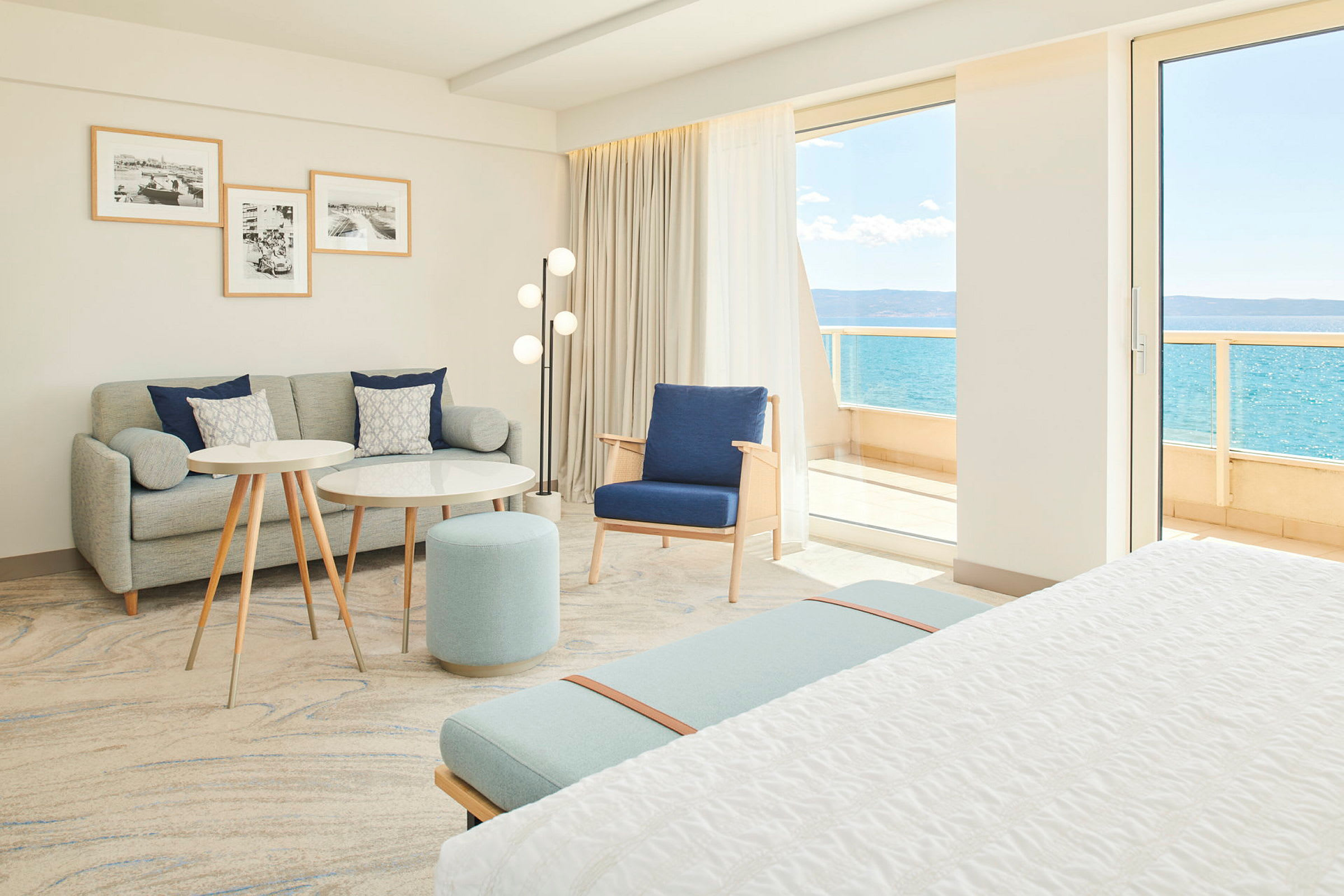 Valoisa ja moderni hotellihuone, jossa istuinryhmä ja merinäköala. (Tekoälyn luoma teksti)