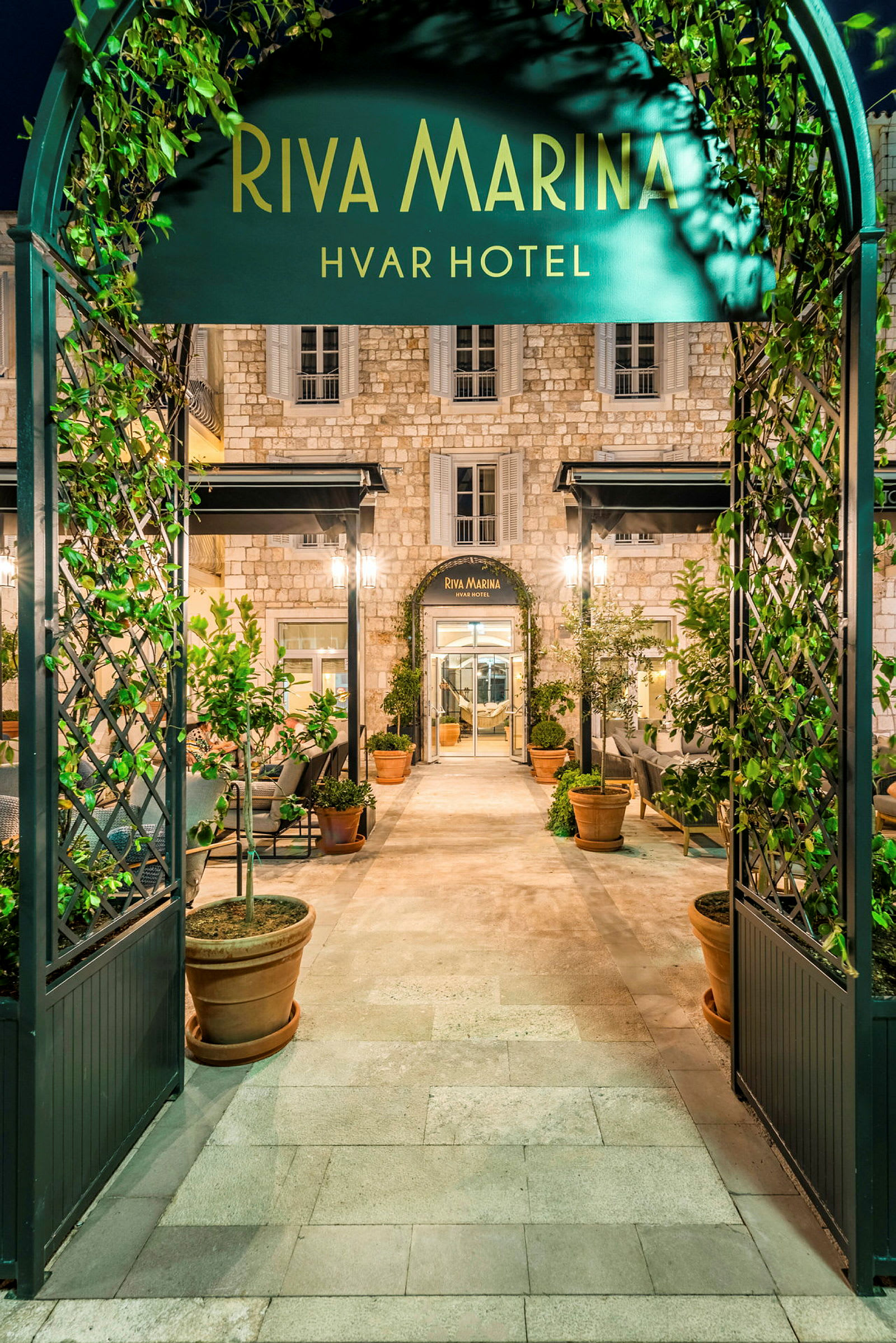Riva Marina Hvar Hotellin sisäänkäynti, jossa on vehreitä kasveja ja tyylikästä arkkitehtuuria. (Tekoälyn luoma teksti)