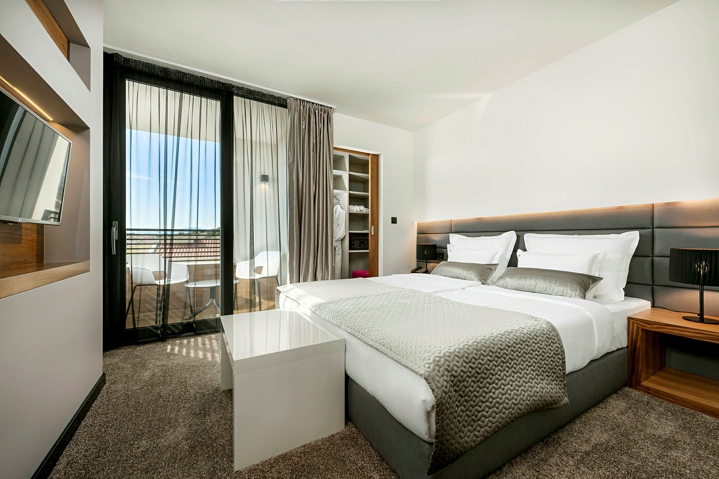 Moderni hotellihuone, jossa parivuode ja parveke. (Tekoälyn luoma teksti)