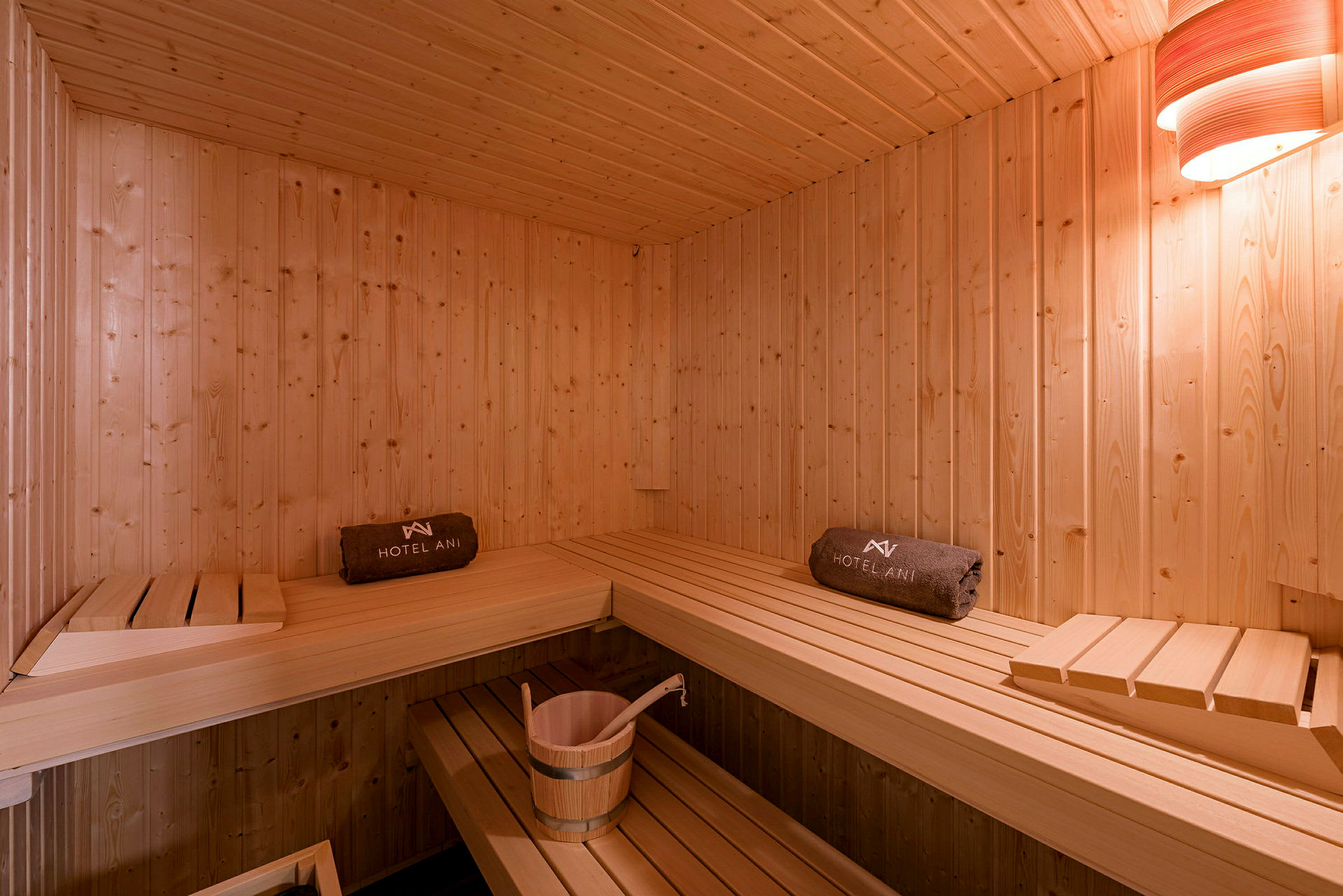 Puisesti sisustettu sauna, jossa on istumapaikkoja ja ämpäri. (Tekoälyn luoma teksti)