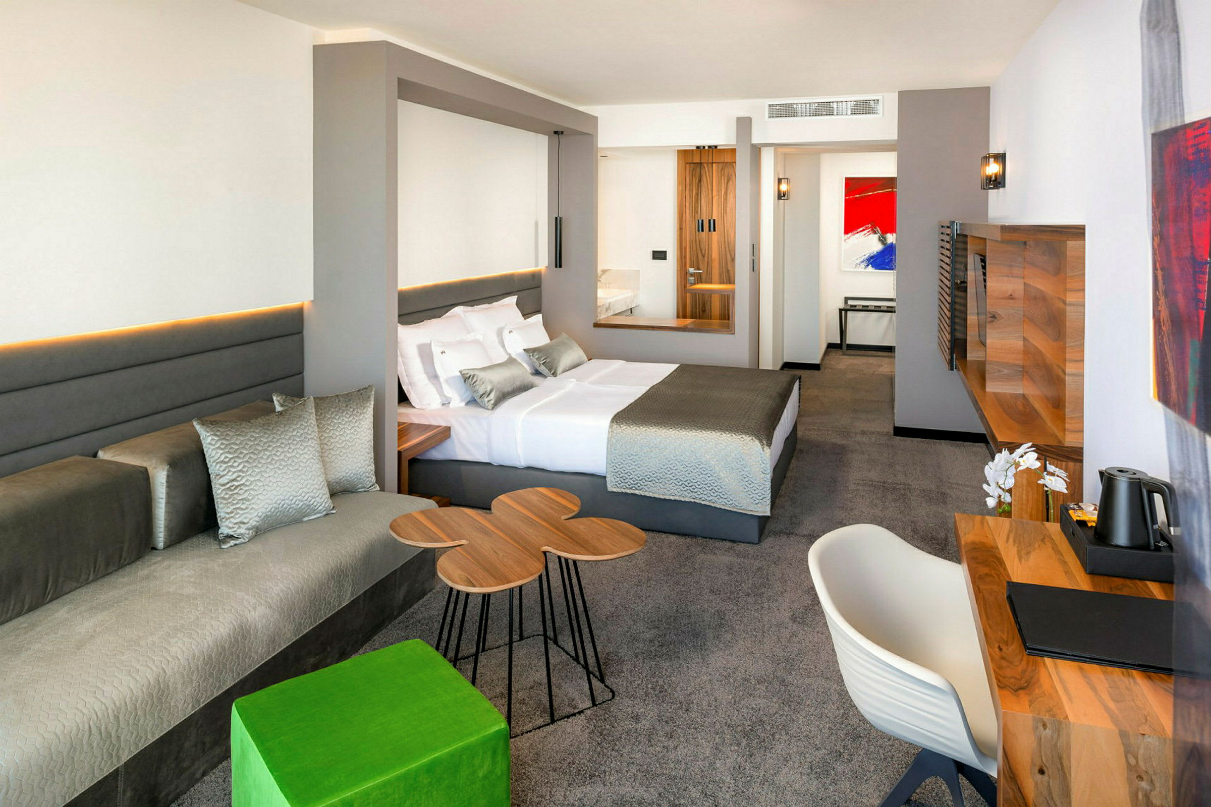 Moderni hotellihuone, jossa on iso sänky, kirjoituspöytä ja istuma-alue. (Tekoälyn luoma teksti)