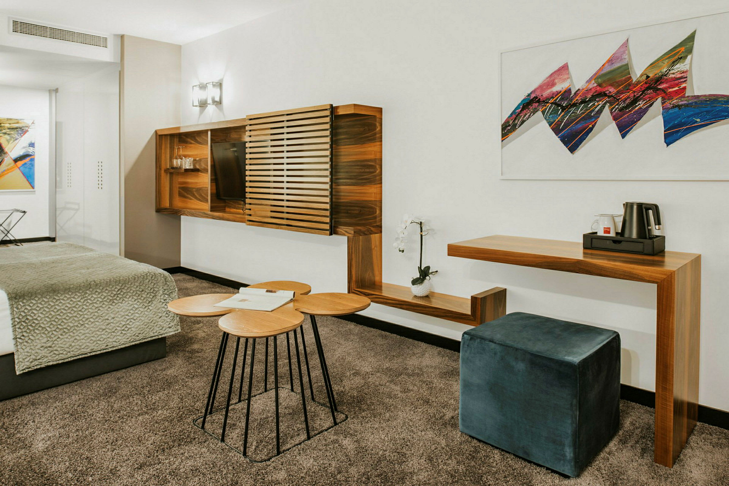 Moderni hotellihuone, jossa puukalusteet, istumajakkara ja taidetta seinällä. (Tekoälyn luoma teksti)