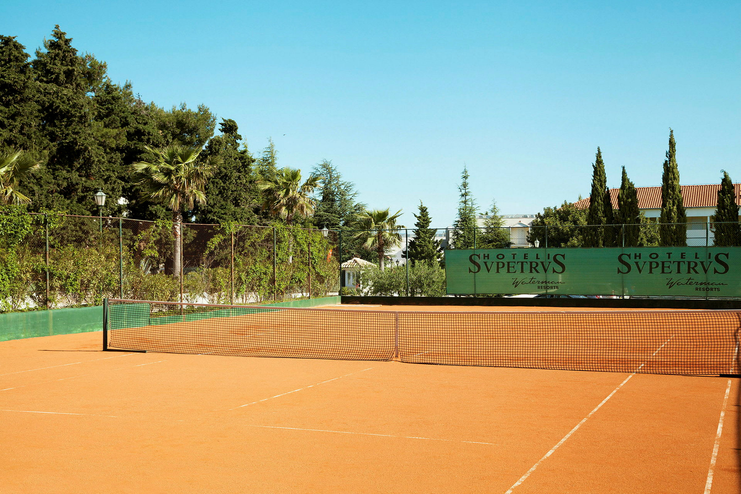 Tenniskenttä ympäröivillä puilla ja pensailla. (Tekoälyn luoma teksti)