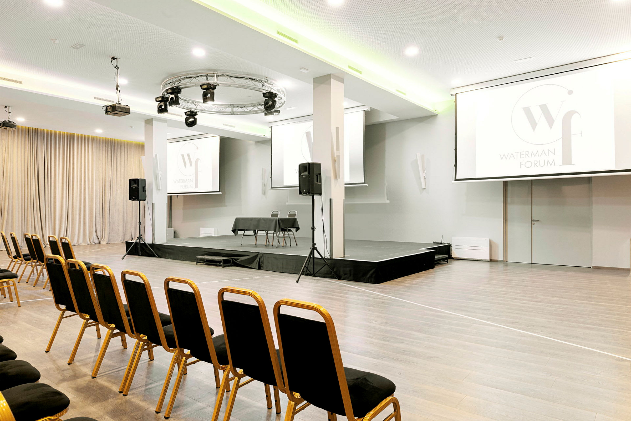 Konferenssihuone, jossa on lava ja tuolit edessä. (Tekoälyn luoma teksti)
