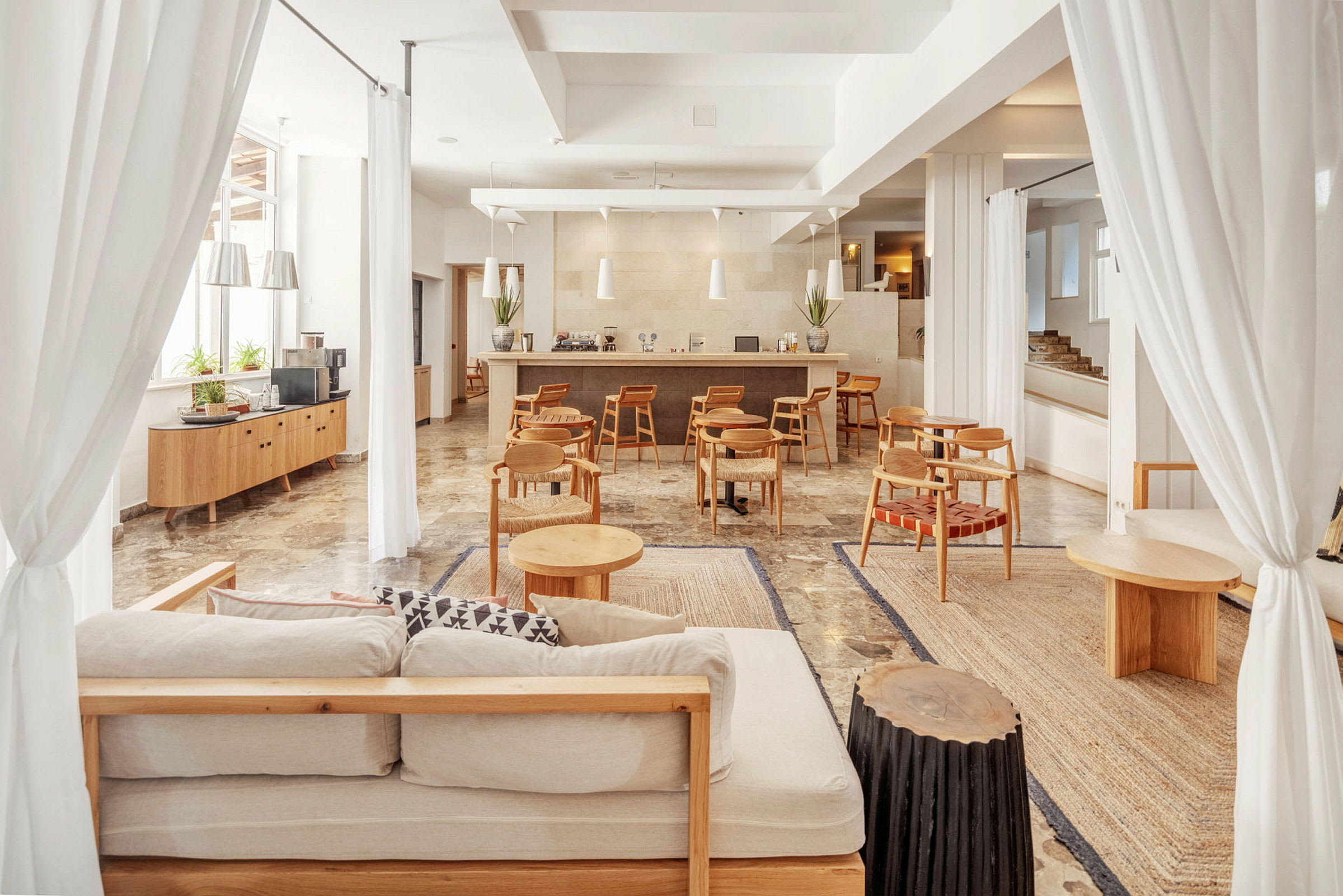 Valoisa ja tilava lounge-alue, jossa sohvia, pieniä puupöytiä ja baaritiski taustalla. (Tekoälyn luoma teksti)