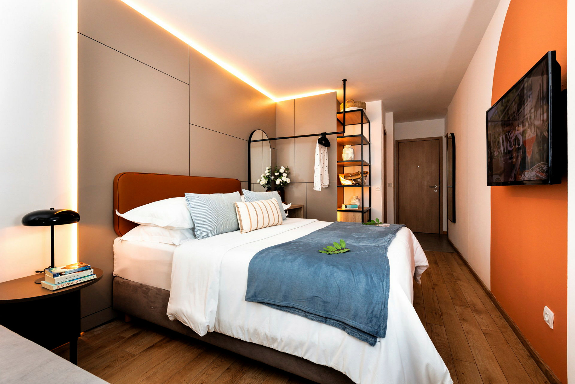 Moderni hotellihuone, jossa parivuode, koristeelliset tyynyt ja valaistus. (Tekoälyn luoma teksti)