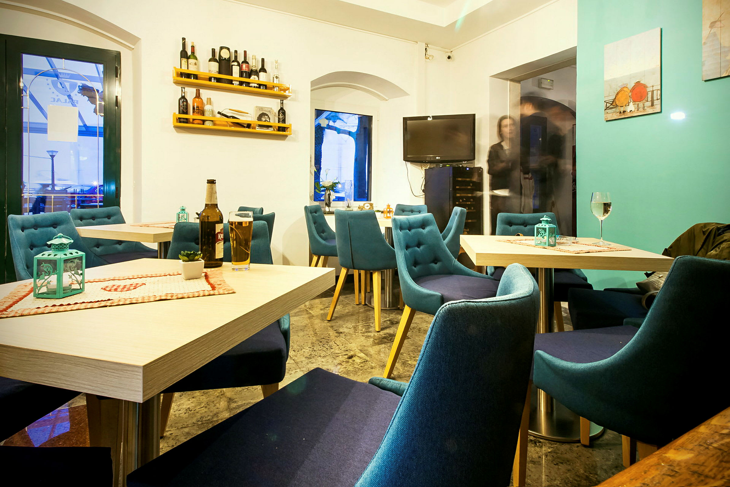 Vaalea ja viihtyisä ravintola, jossa on siniset tuolit ja katetut pöydät. (Tekoälyn luoma teksti)