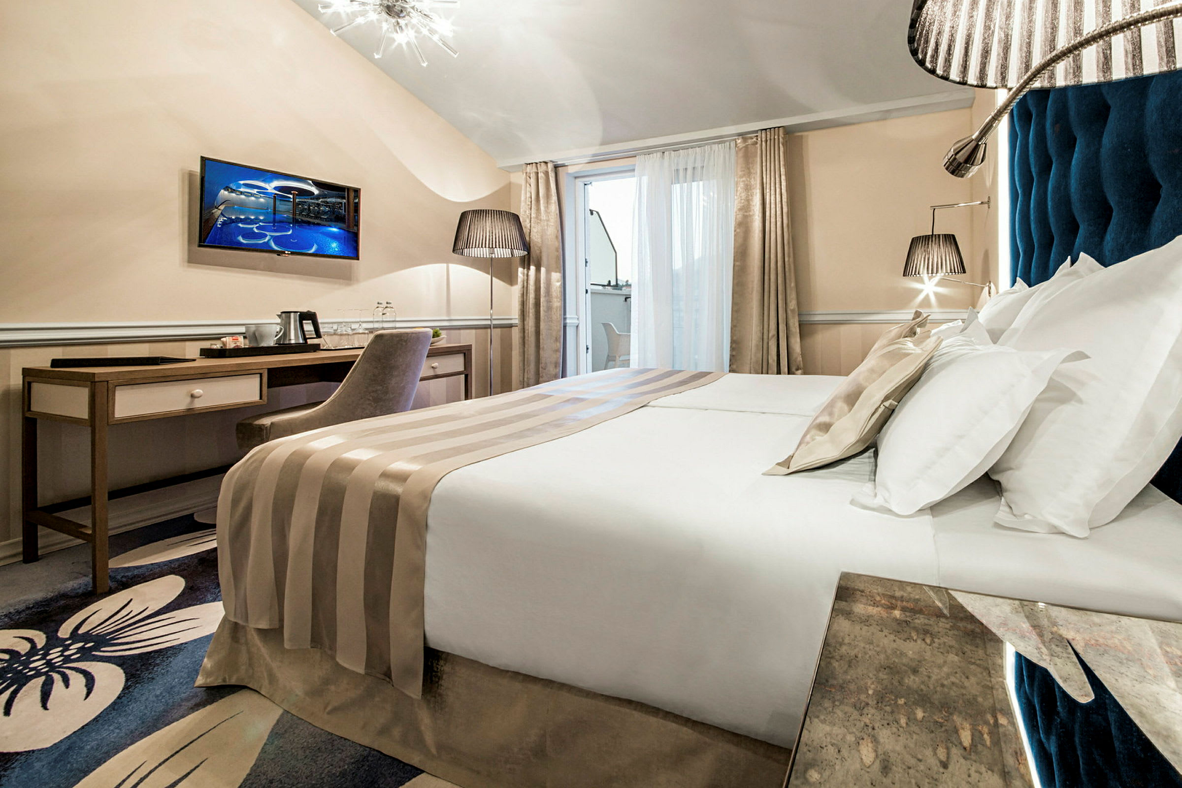Moderni hotellihuone, jossa parivuode, työpöytä, tuoli ja televisio. (Tekoälyn luoma teksti)