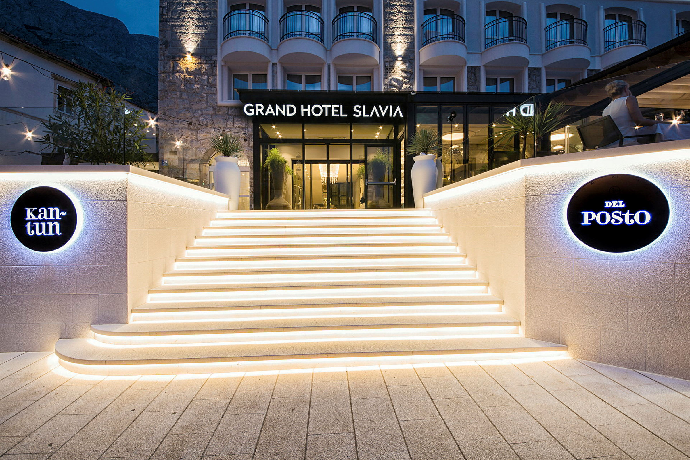 Grand Hotel Slavian sisäänkäynti, jossa valaistut portaat ja opasteet. (Tekoälyn luoma teksti)