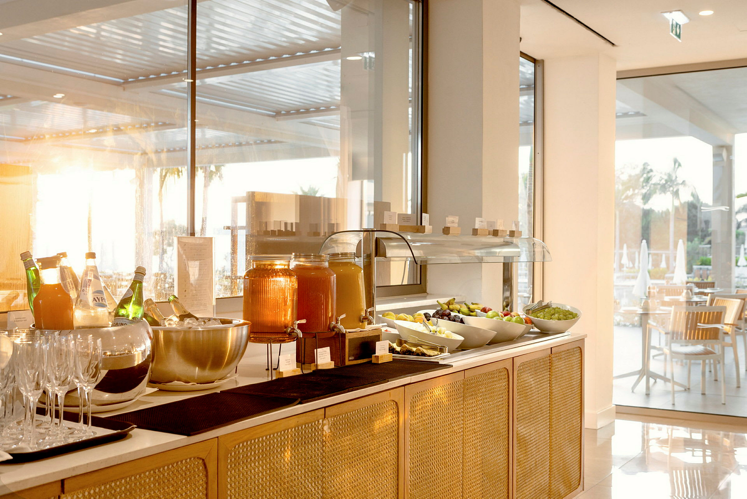 Buffet keittiötarvikkeilla, mehulla ja tuoreilla hedelmillä valoisassa huoneessa. (Tekoälyn luoma teksti)