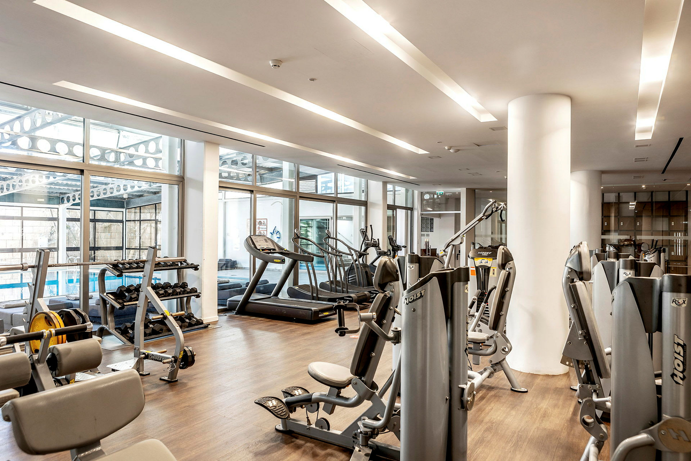 Kuntosali, jossa fitnessvälineitä ja suuret ikkunat. (Tekoälyn luoma teksti)
