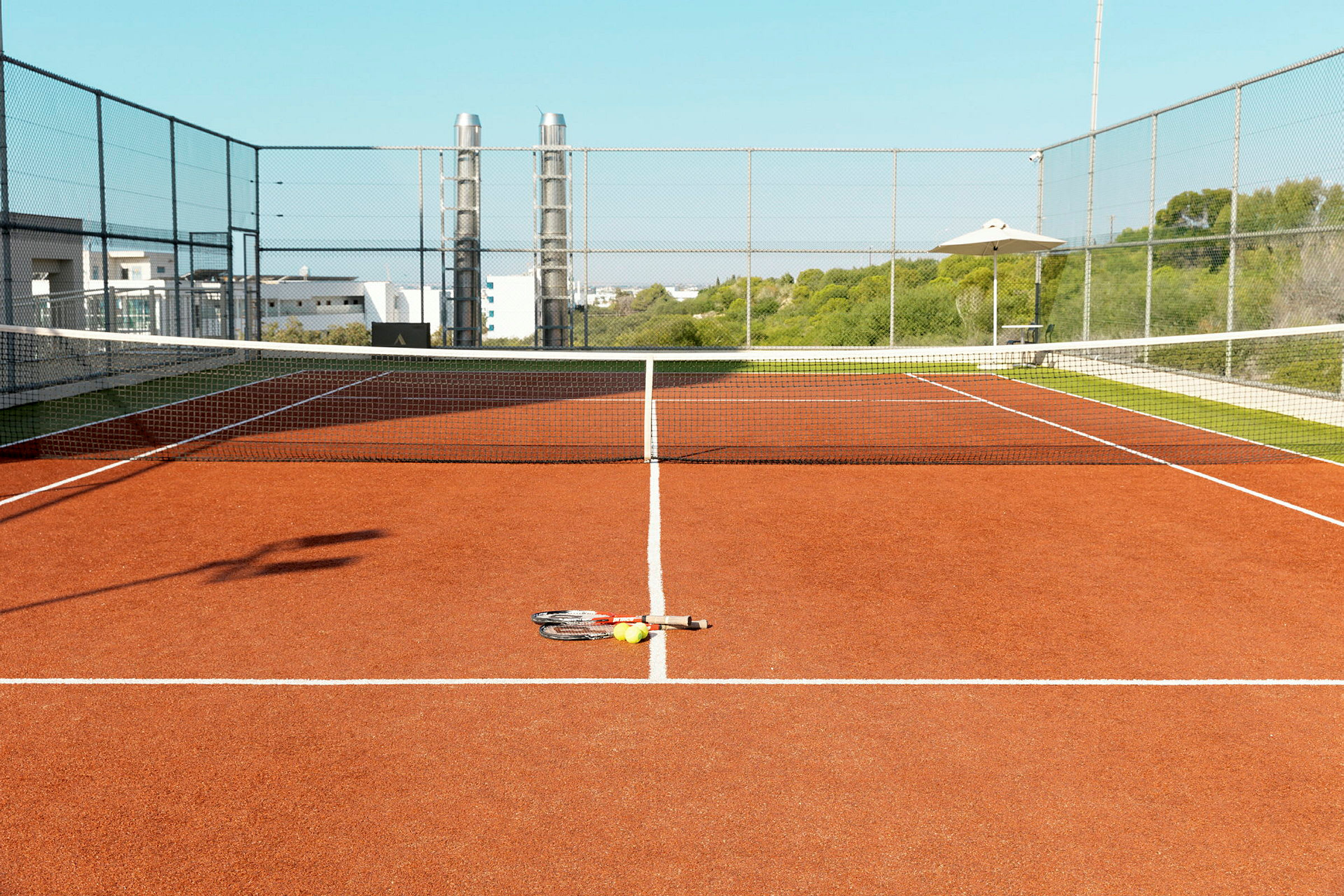 Kuva tenniskentästä, jossa on maila ja palloja maassa. (Tekoälyn luoma teksti)