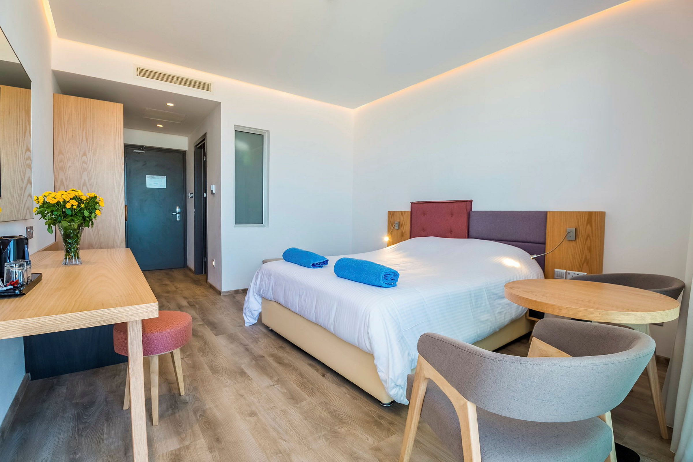 Hotellihuone, jossa on parivuode, pöytä tuoleilla ja kirjoituspöytätila. (Tekoälyn luoma teksti)