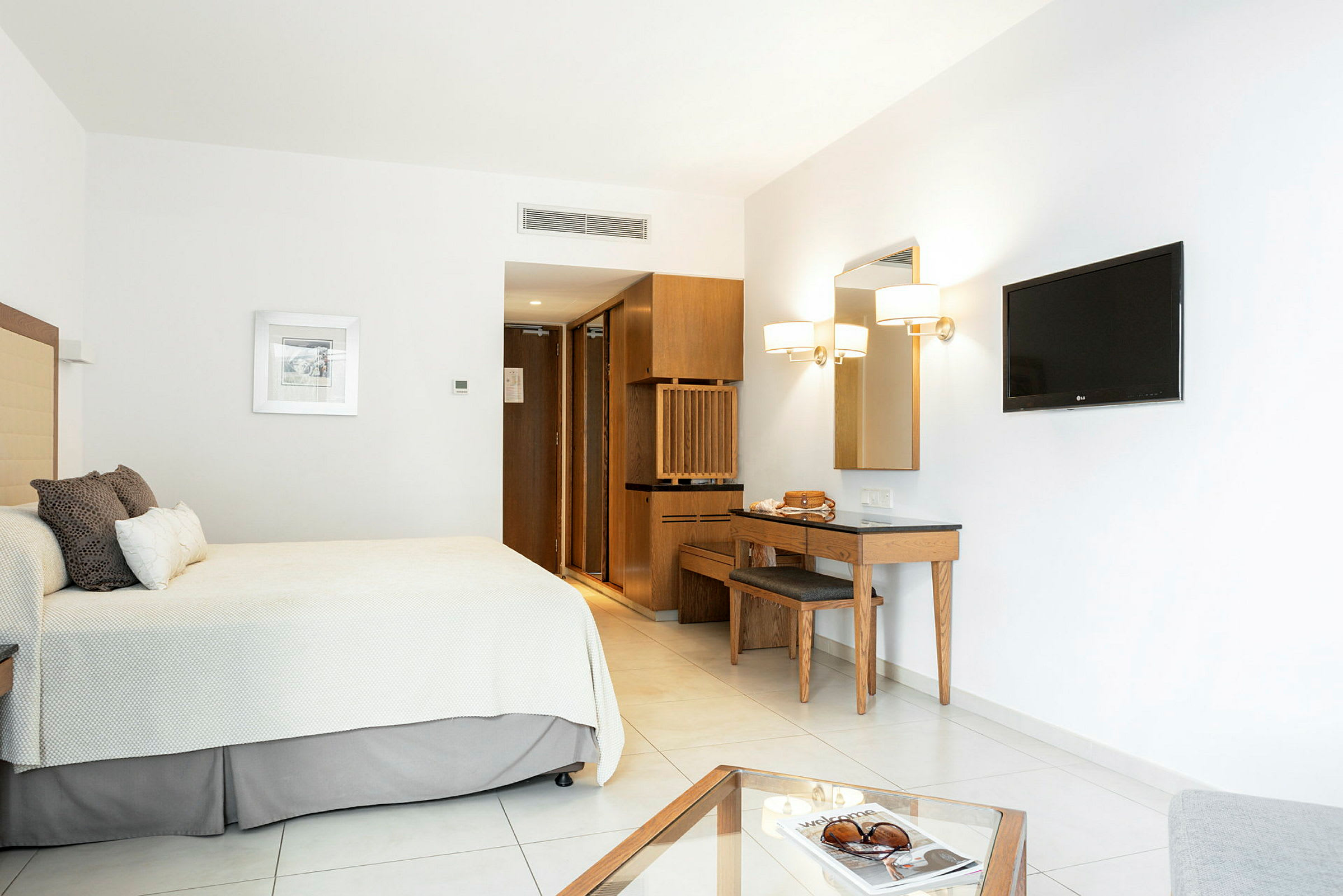 Minimalistinen hotellihuone, jossa vuode, seinälle kiinnitetty televisio ja kirjoituspöytä. (Tekoälyn luoma teksti)