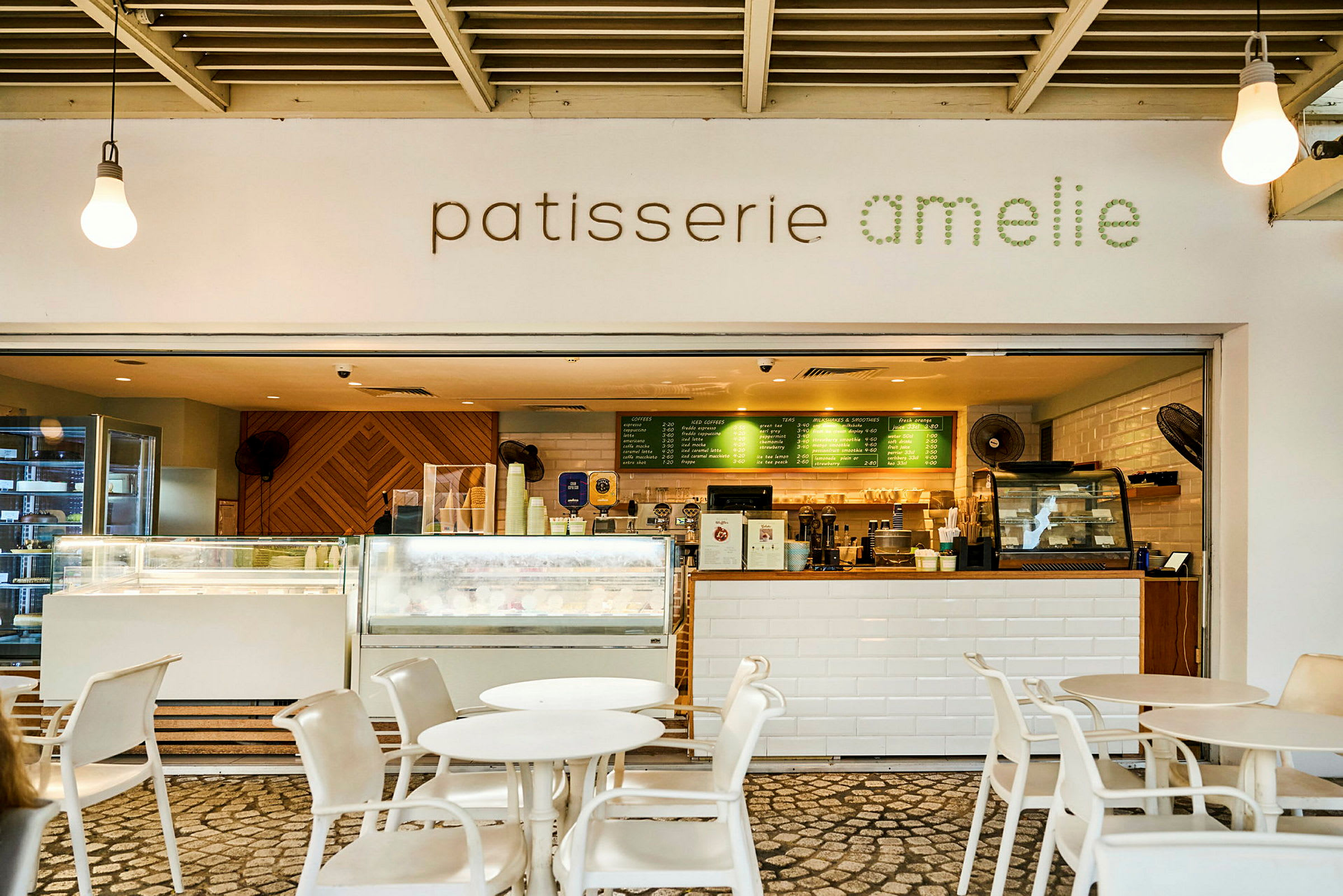 Kahvila, jossa kyltti "patisserie amelie" ja kutsuva tarjoilutiski pöytineen ja tuoleineen edessä. (Tekoälyn luoma teksti)