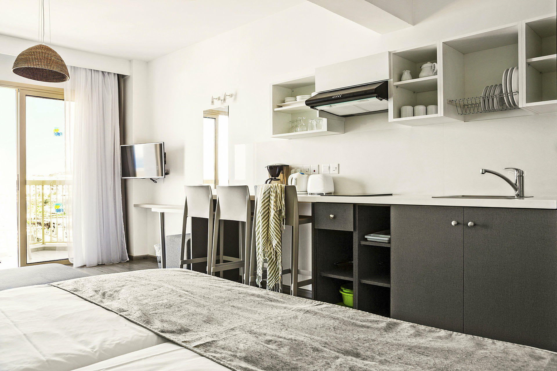 Hotellihuone, jossa keittiötila, sänky ja parveke. (Tekoälyn luoma teksti)