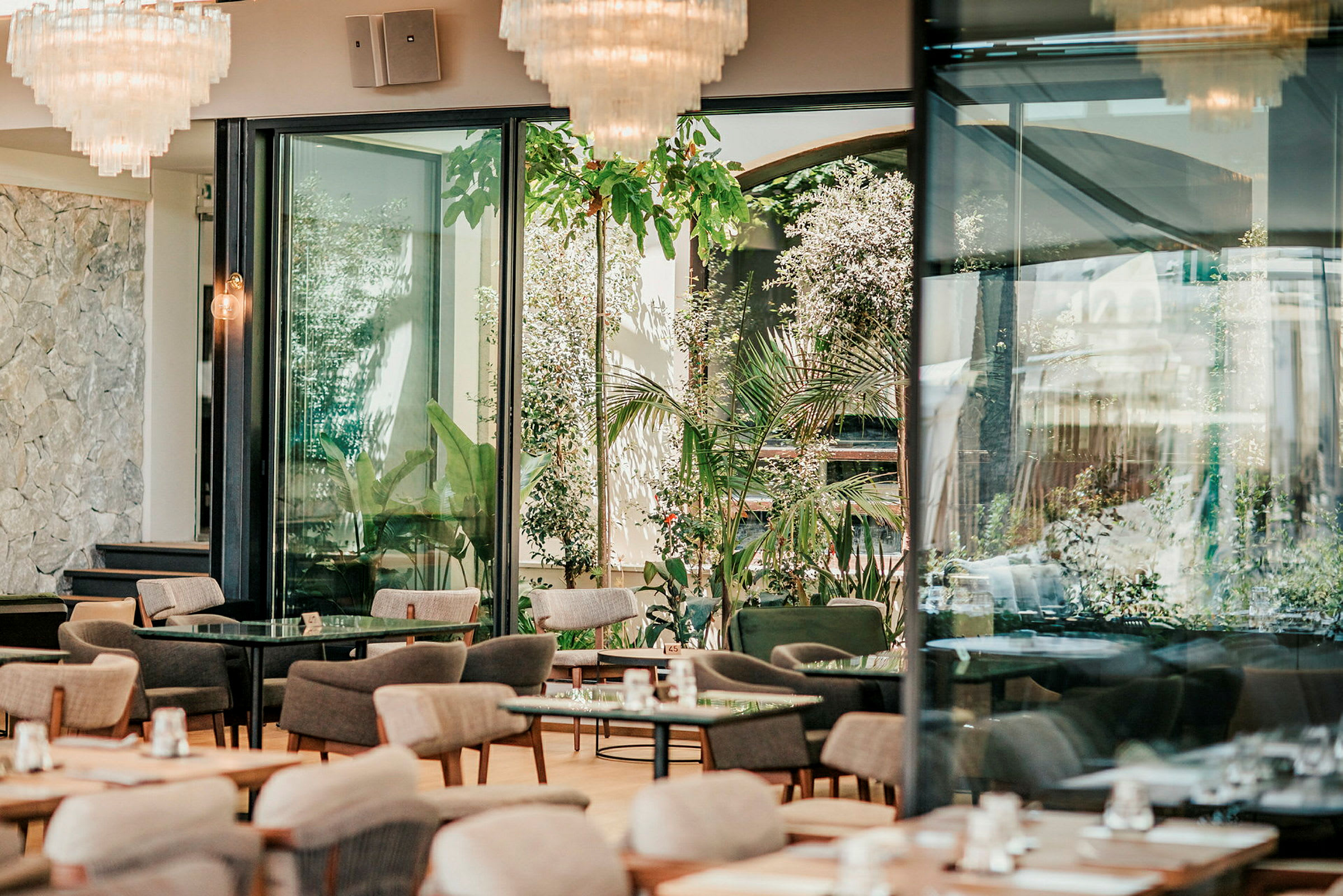 Moderni, hyvin valaistu ravintola, jossa on suuret ikkunat ja ulkona vihreyttä. (Tekoälyn luoma teksti)