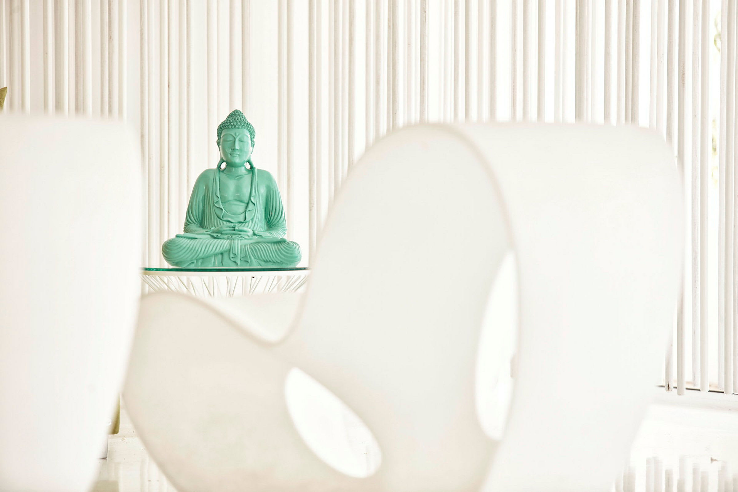 Vihreä Buddha-patsas asetettuna pöydälle minimalistista taustaa vasten. (Tekoälyn luoma teksti)