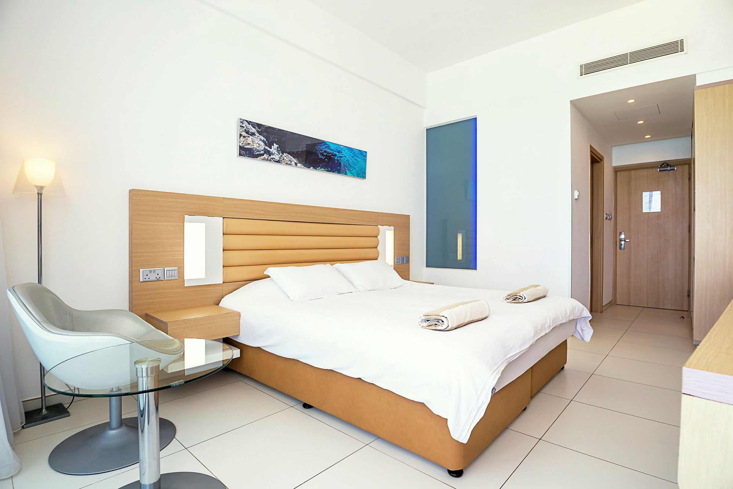 Moderni hotellihuone, jossa parivuode, tuoli ja pöytä. (Tekoälyn luoma teksti)