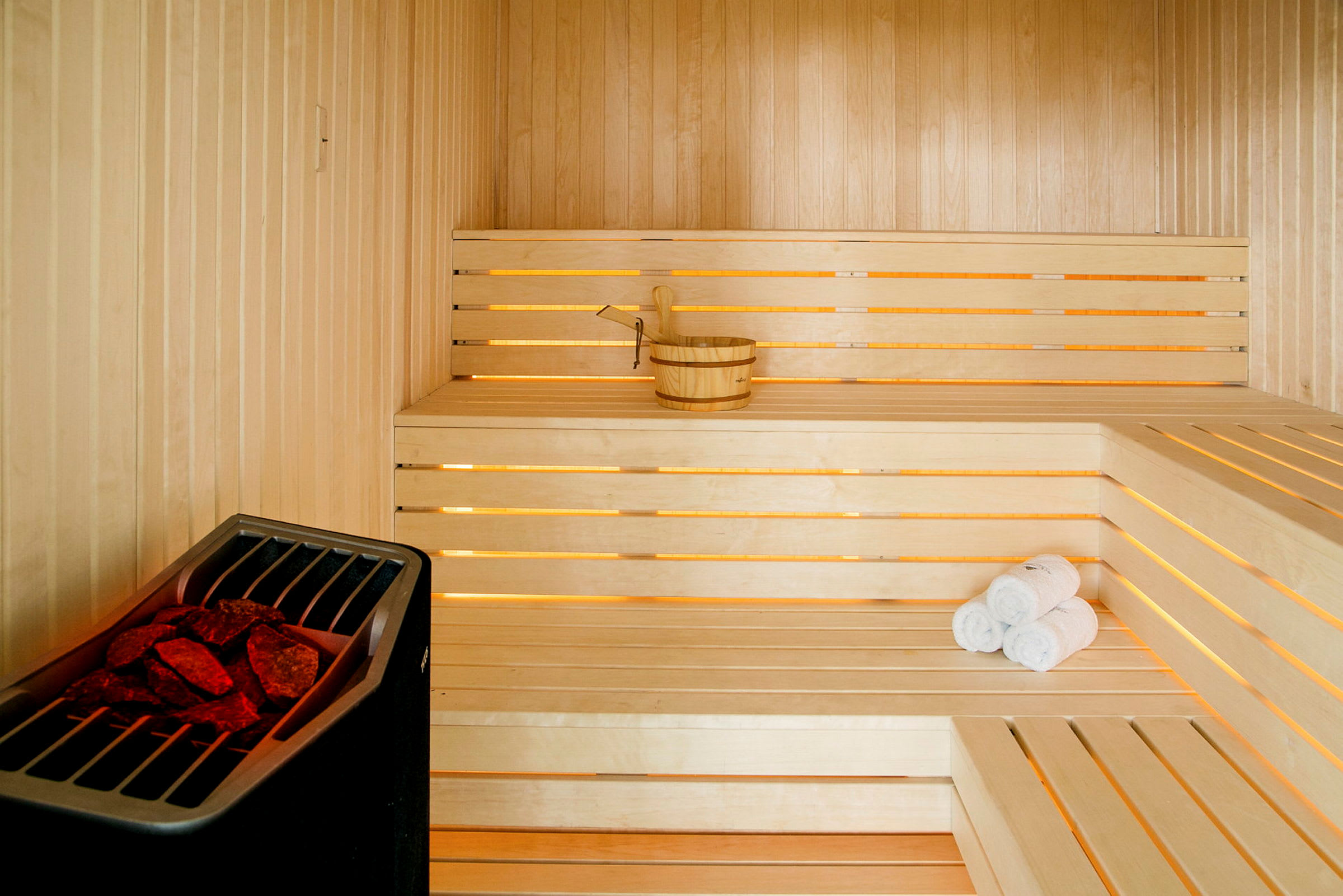 Puinen sauna, jossa on penkit, sanko ja pyyhkeet. (Tekoälyn luoma teksti)