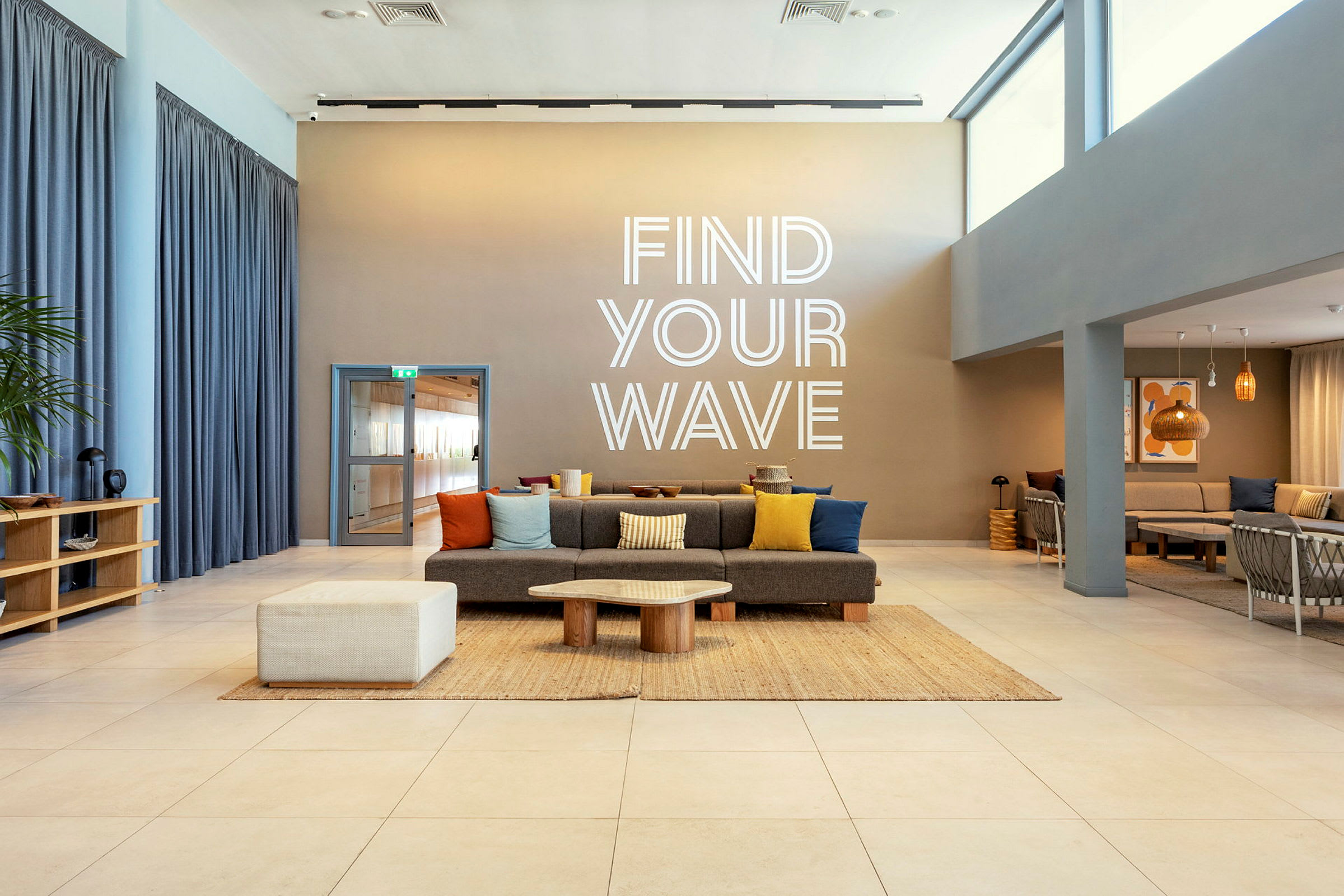 Moderni huone, jossa istumapaikkoja ja tekstinä seinällä 'Find Your Wave'. (Tekoälyn luoma teksti)