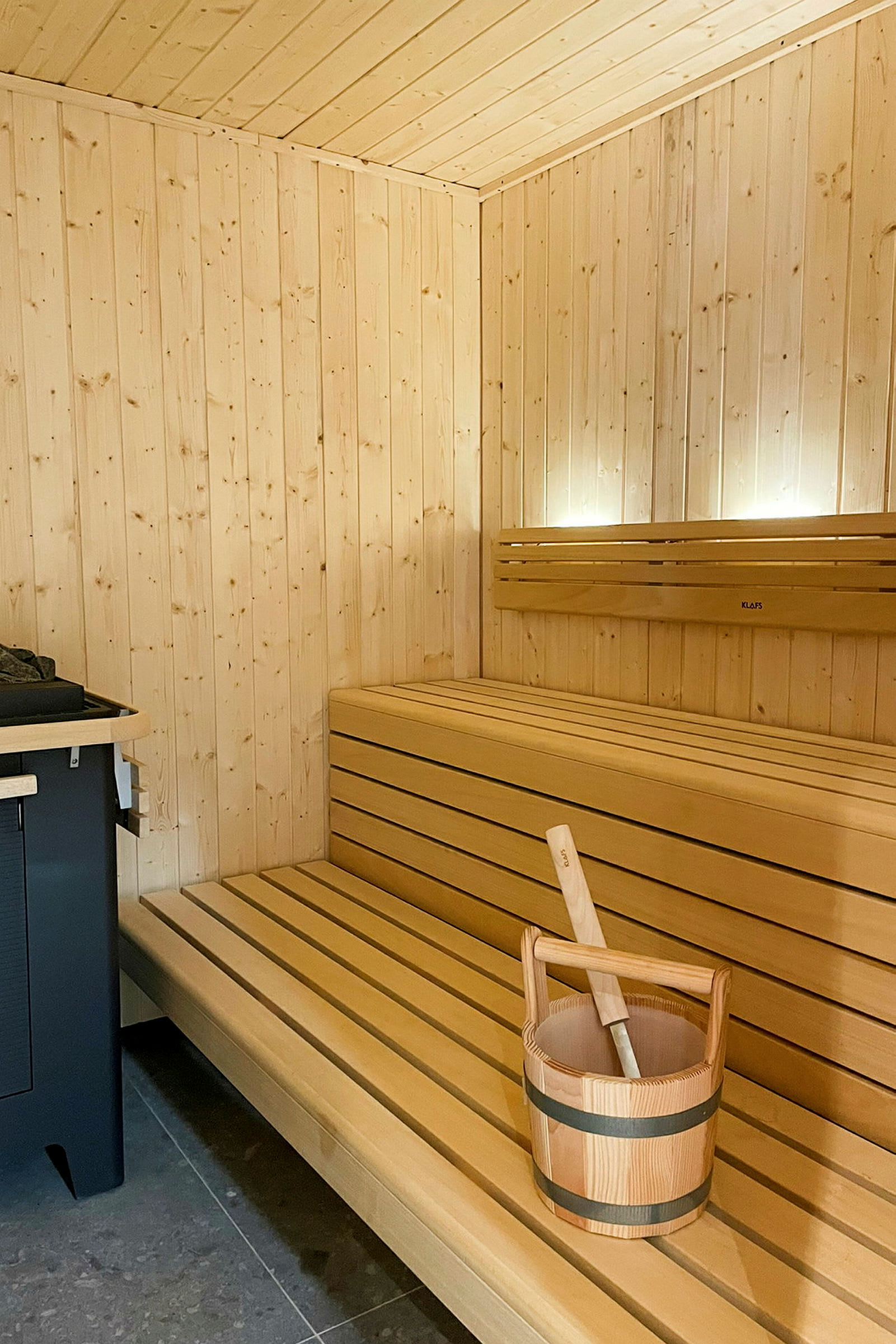 Sauna, jossa puupaneelit, puupenkki ja kauha ämpärillä höyryyn. (Tekoälyn luoma teksti)