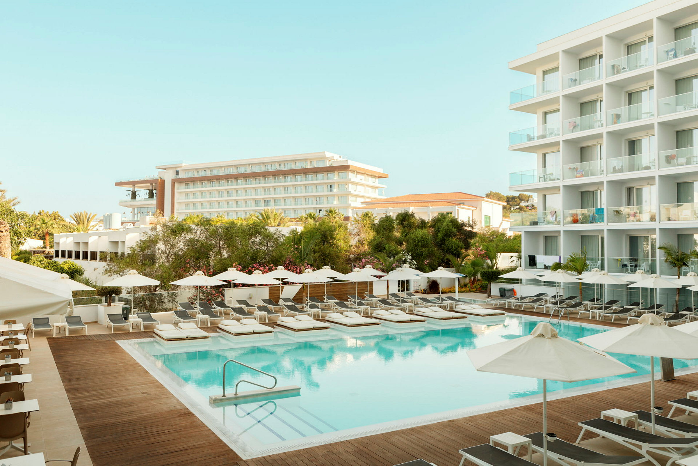 Hotellialue, jossa uima-allas, aurinkotuoleja ja taustalla rakennuksia. (Tekoälyn luoma teksti)