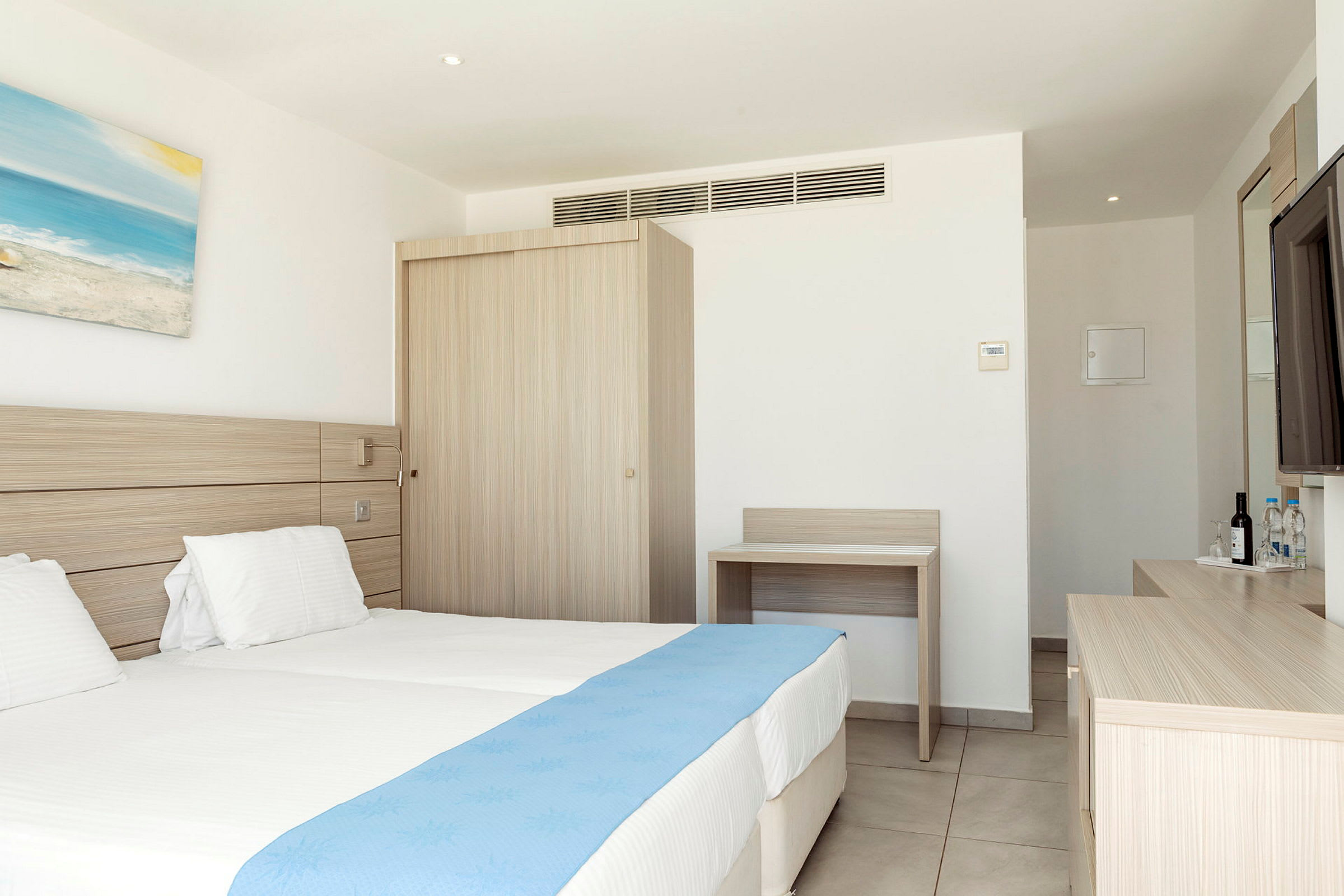 Hotellihuone, jossa kaksi yhden hengen sänkyä ja sininen päiväpeite. (Tekoälyn luoma teksti)
