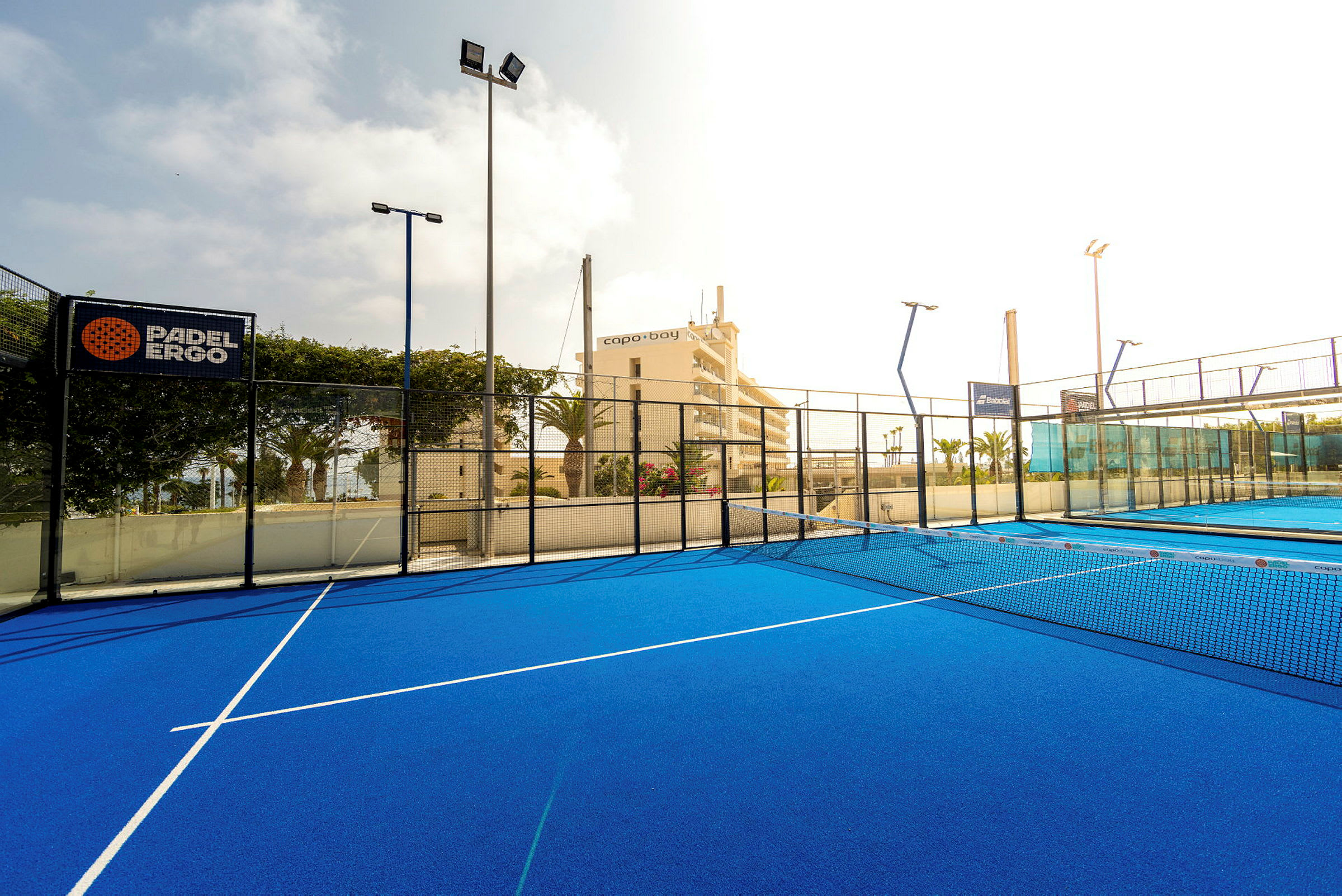 Padel-kenttä, jonka sininen pinta ja verkko sekä ympäröivät aidat. (Tekoälyn luoma teksti)