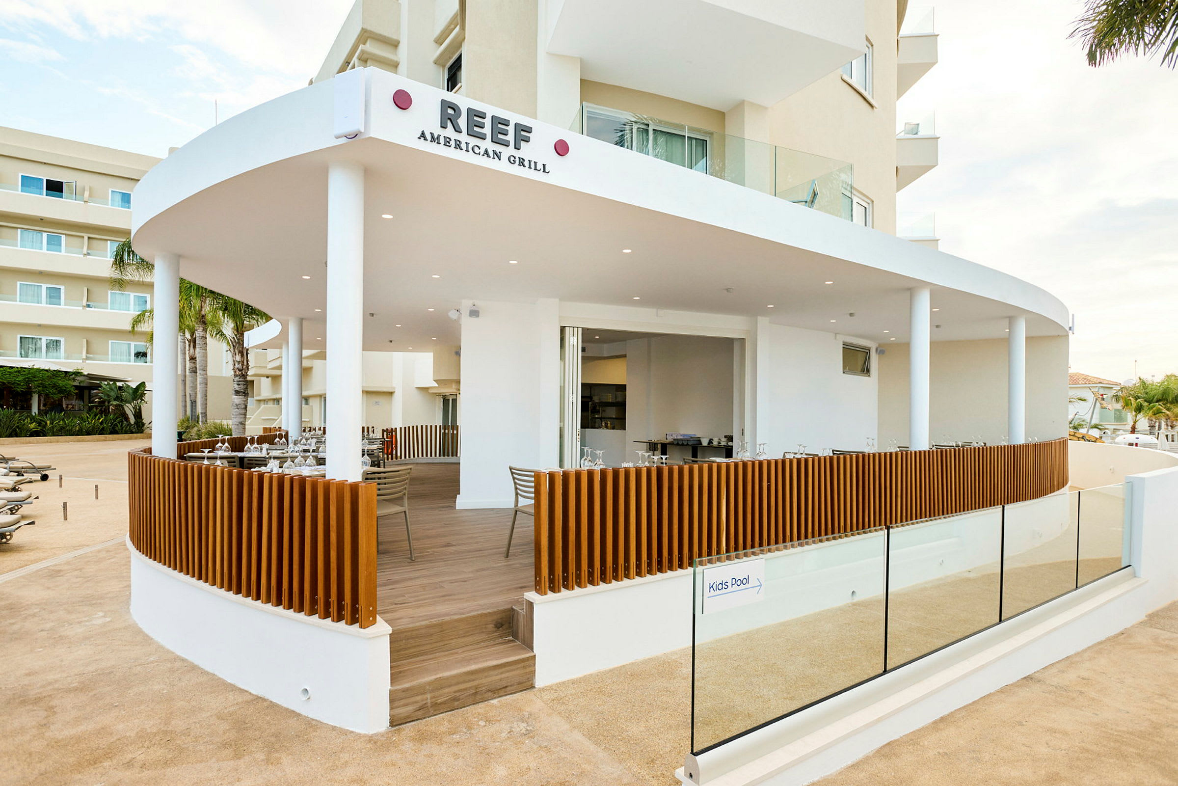 Kuva ravintolasta, Reef American Grill, jossa on avoin terassi ja moderni design. (Tekoälyn luoma teksti)