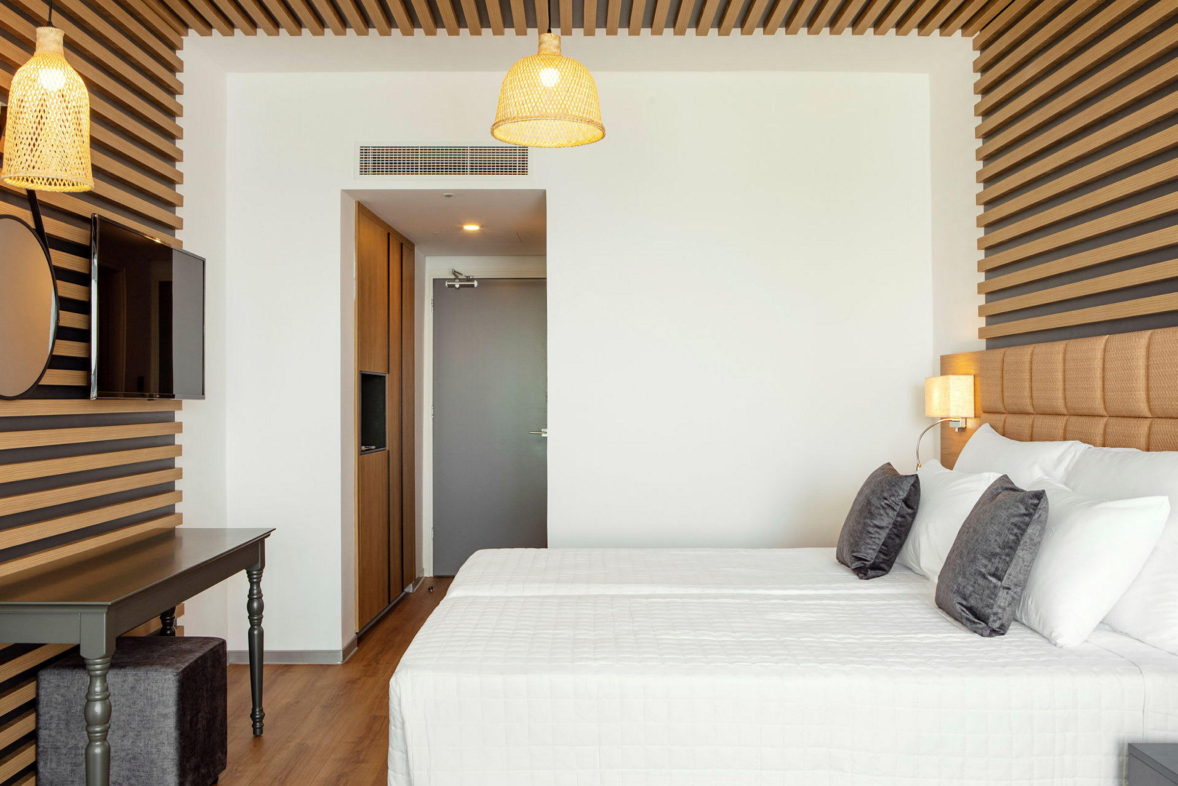 Moderni hotellihuone, jossa on parivuode, puusisusteita ja valaisimia. (Tekoälyn luoma teksti)