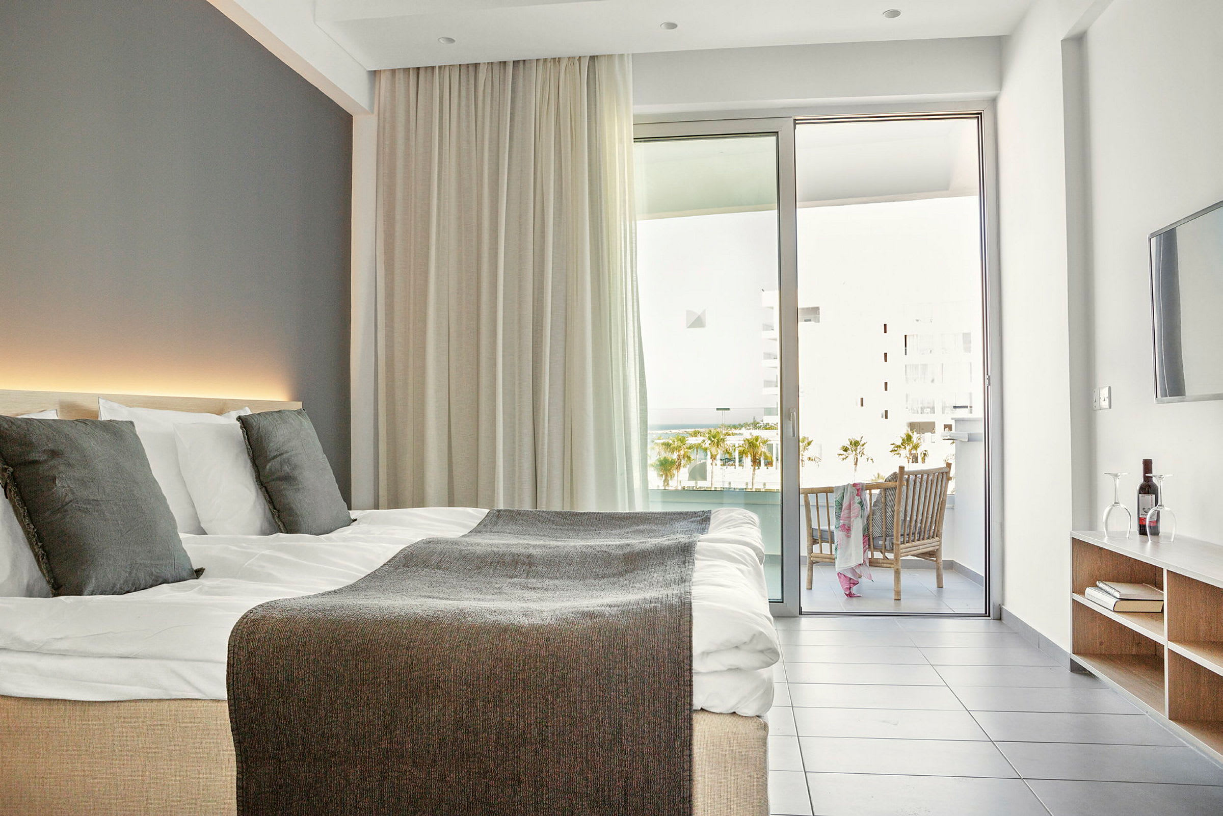 Moderni hotellihuone, jossa parivuode, parveke ja istuinalue. (Tekoälyn luoma teksti)
