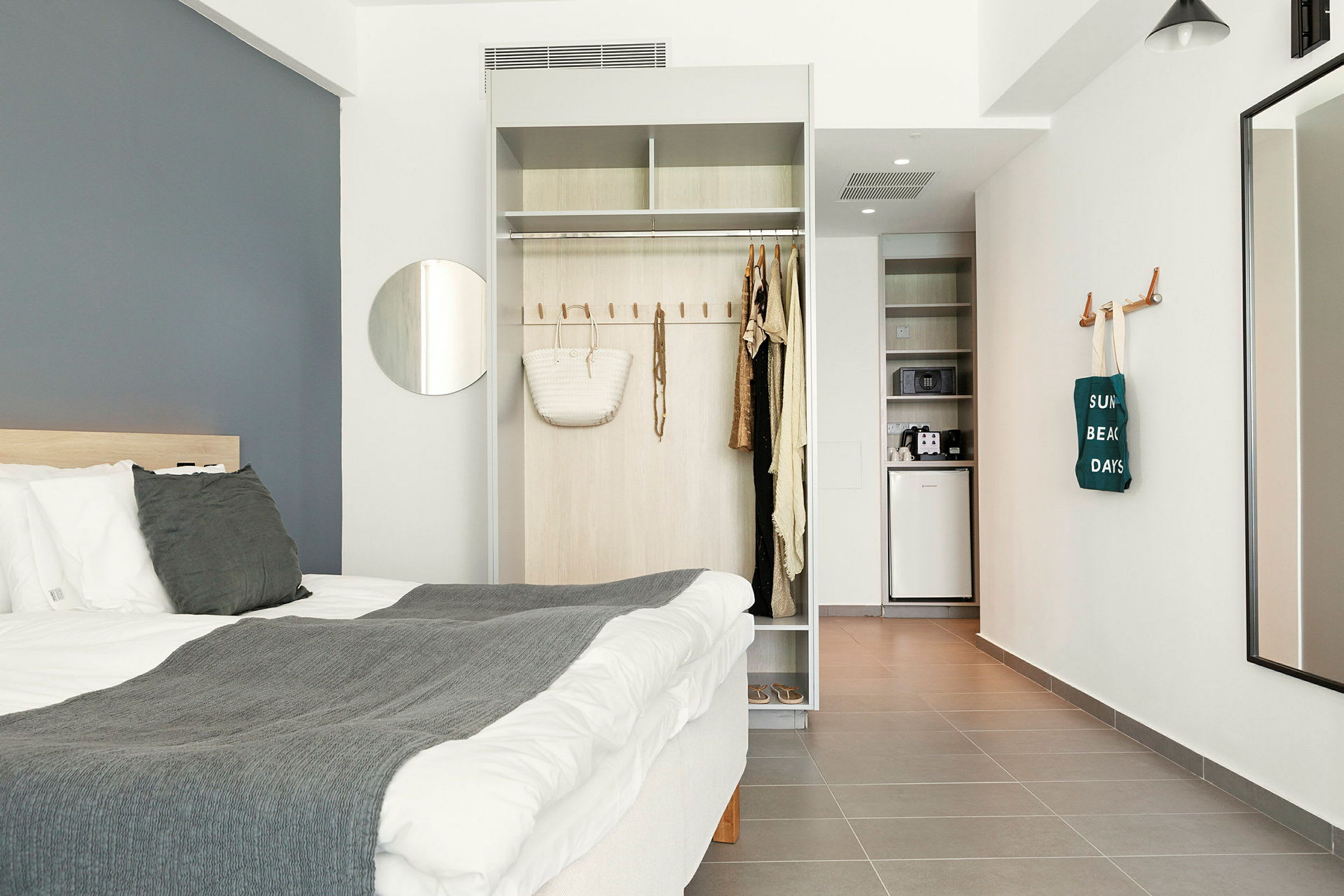 Moderni hotellihuone, jossa on sänky, vaatekaappi ja pieni keittiö. (Tekoälyn luoma teksti)