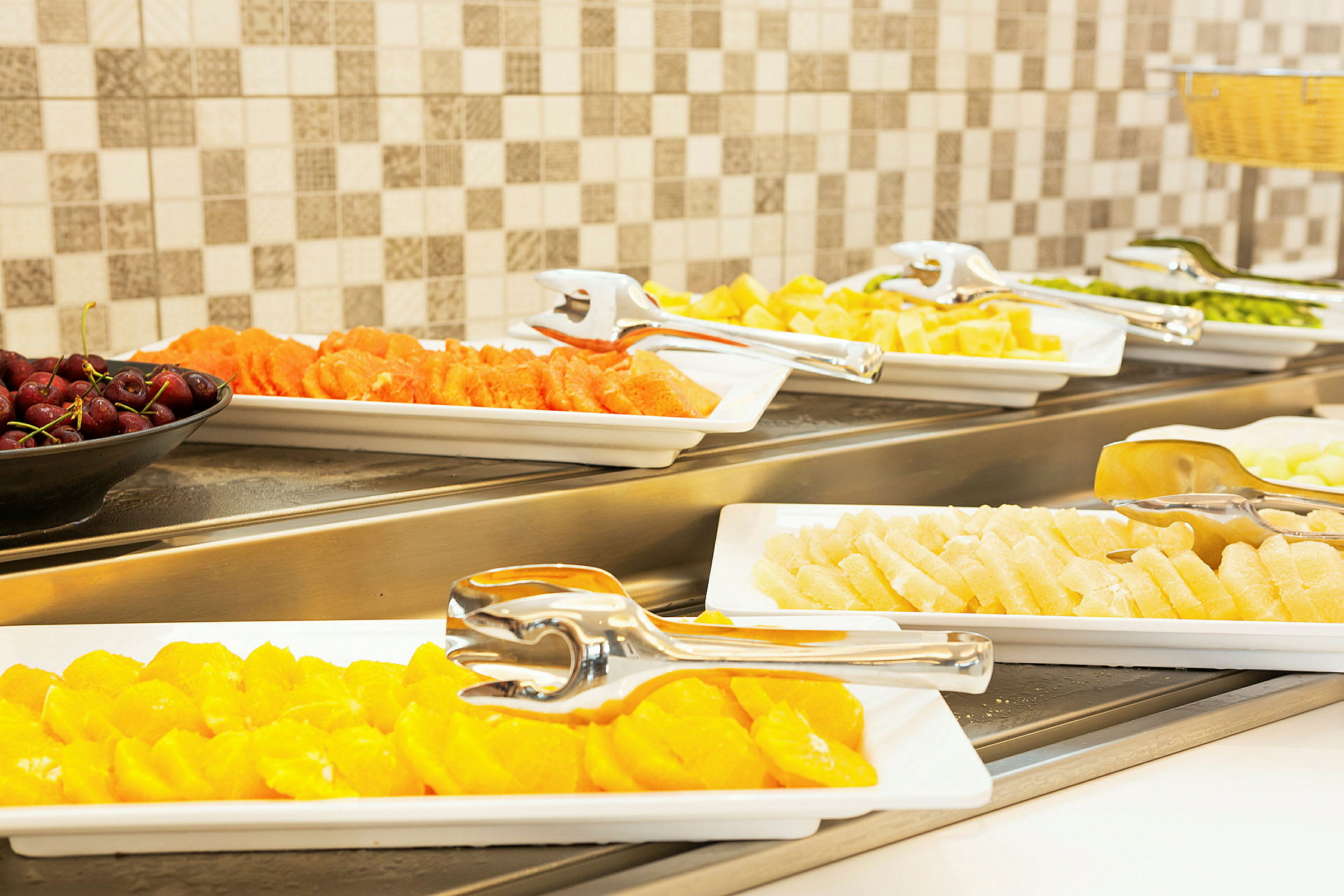 Buffet, jossa on erilaista tuoretta hedelmää tarjoiluastioissa. (Tekoälyn luoma teksti)
