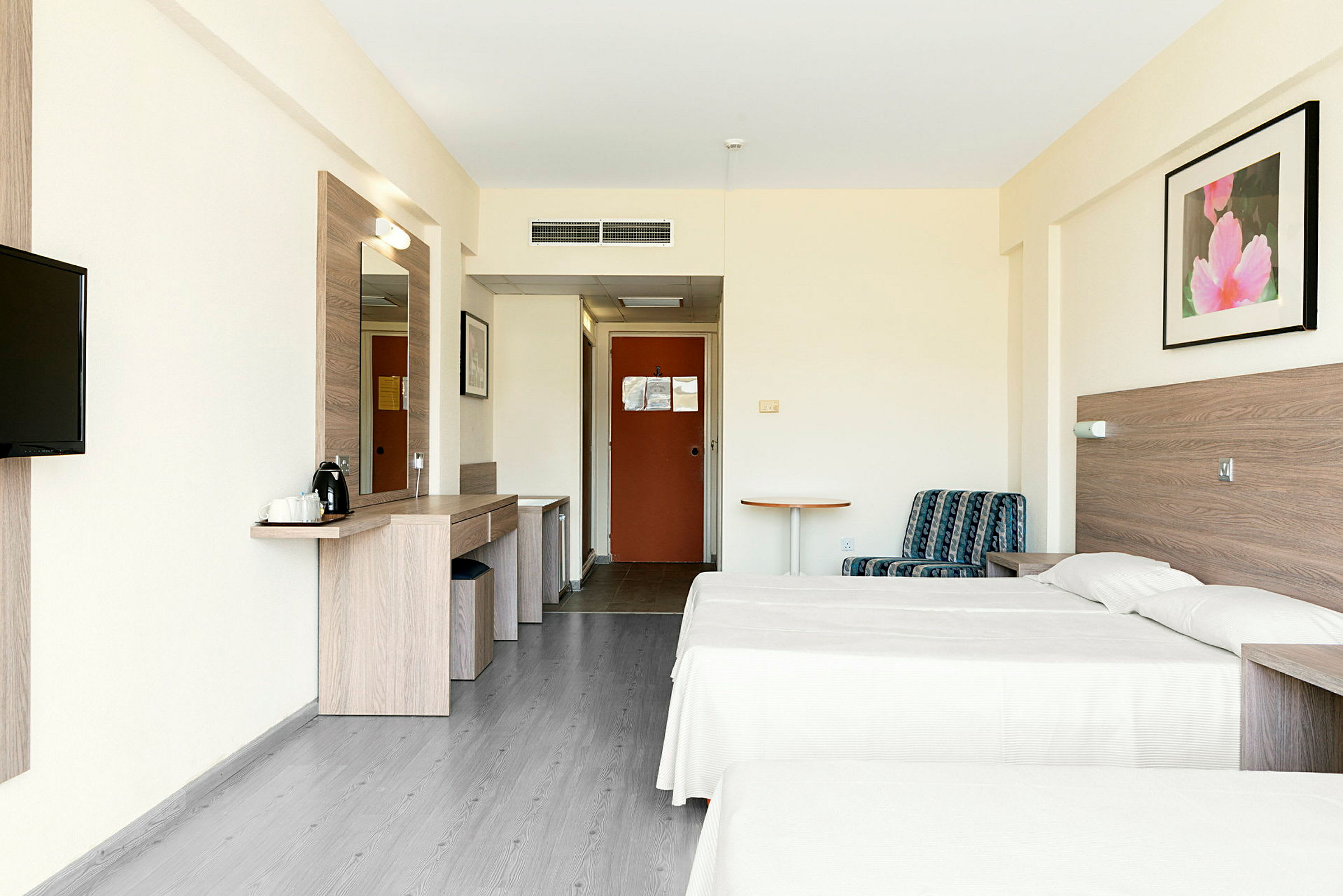 Kuvassa on hotellihuone, jossa on kaksi yhden hengen vuodetta, istumapaikka ja työpöytä. (Tekoälyn luoma teksti)
