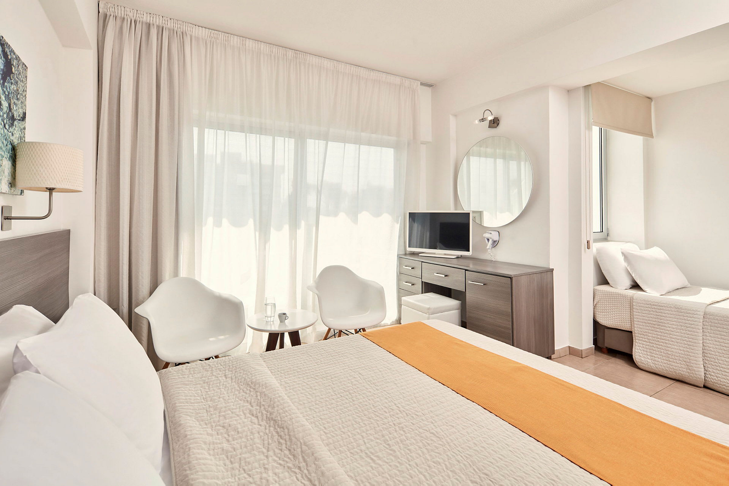 Valoisa ja moderni hotellihuone, jossa on sänky, oleskelutila ja työpöytä. (Tekoälyn luoma teksti)