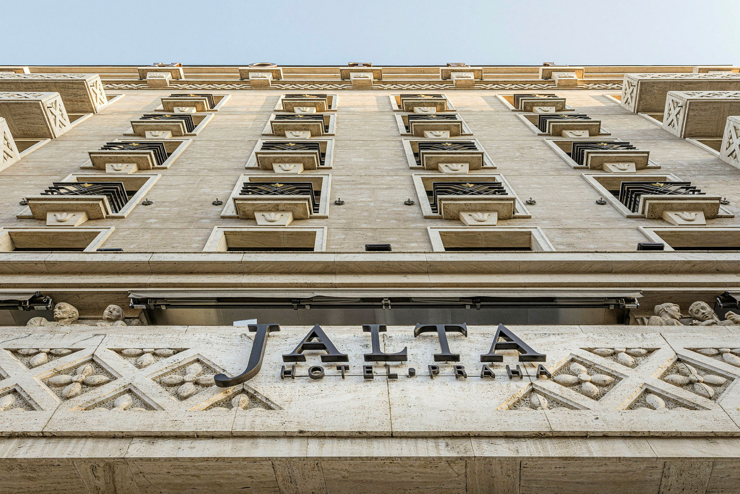 Rakennuksen julkisivu kuvattuna alhaalta ylös, kyltti tekstillä "Jalta Hotel Praha". (Tekoälyn luoma teksti)