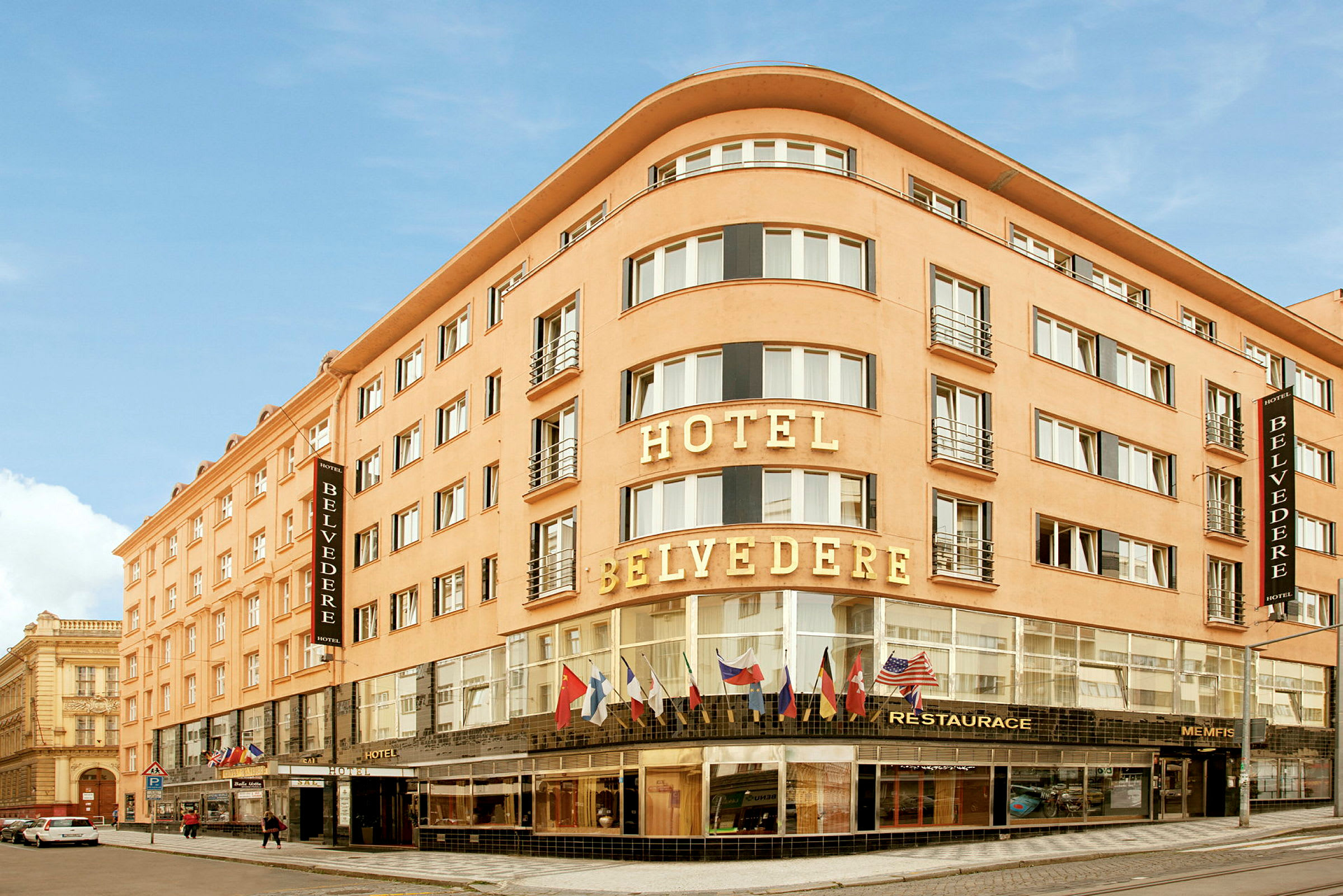 Hotelli nimeltä Hotel Belvedere, usean kerroksen rakennus, jonka lasi-ikkunoiden yläpuolella on lippuja. (Tekoälyn luoma teksti)