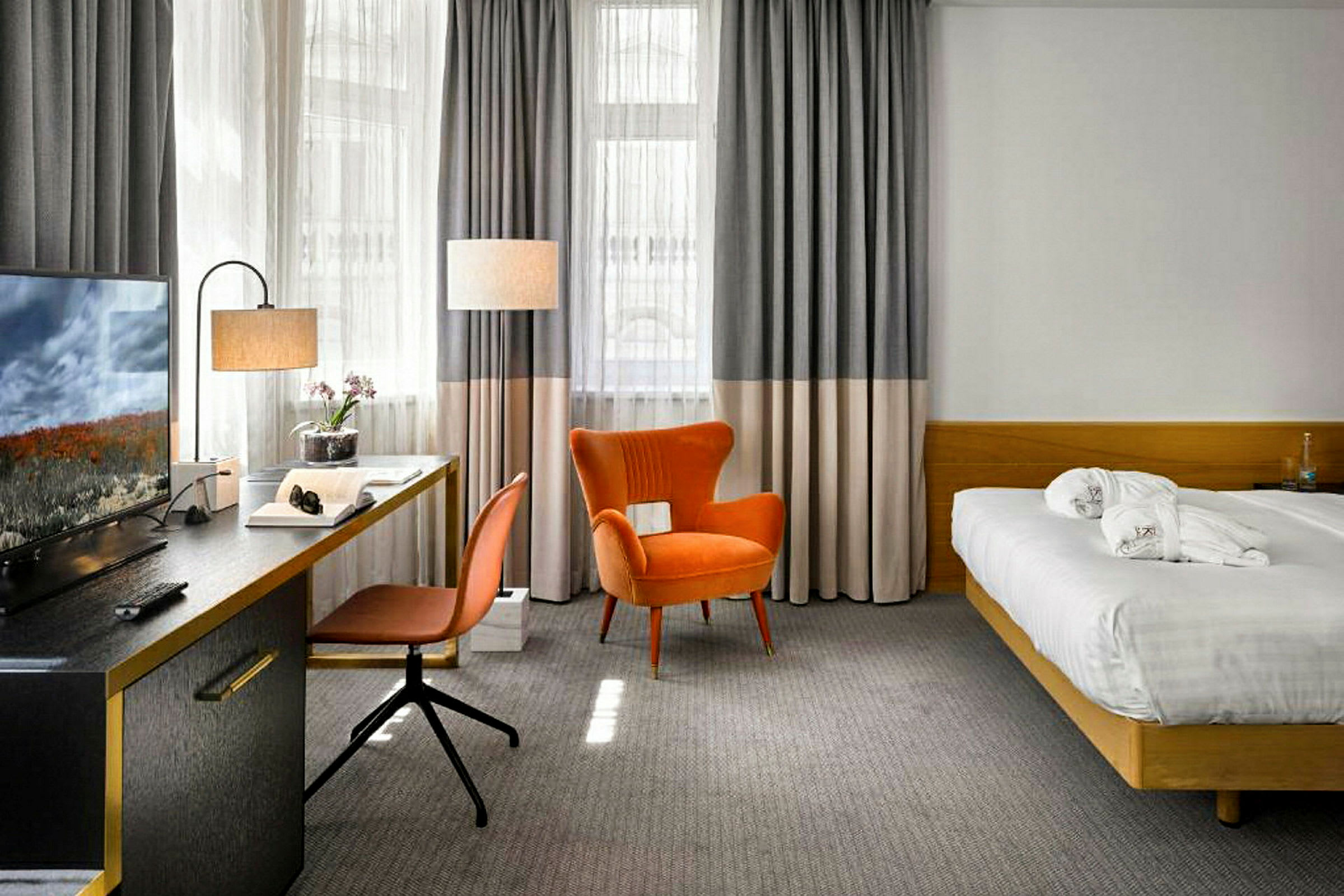 Hotellihuone, jossa on sänky, kirjoituspöytä, tuoli ja nojatuoli. (Tekoälyn luoma teksti)