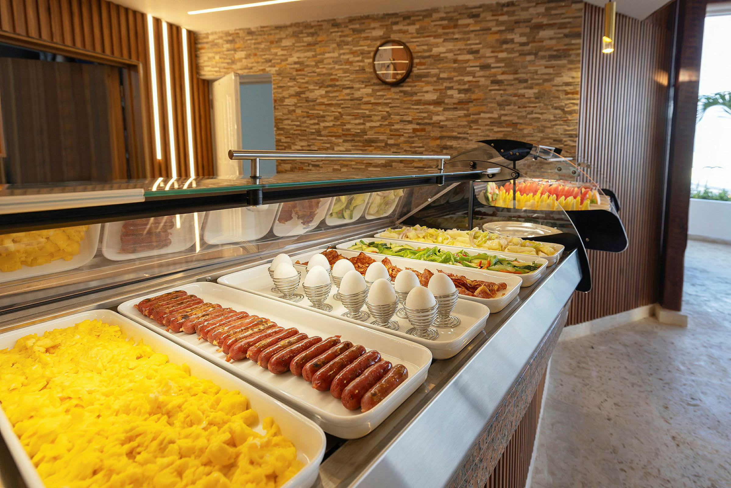 Buffet, jossa aamiaisruokia, kuten munia, makkaroita ja vihanneksia. (Tekoälyn luoma teksti)