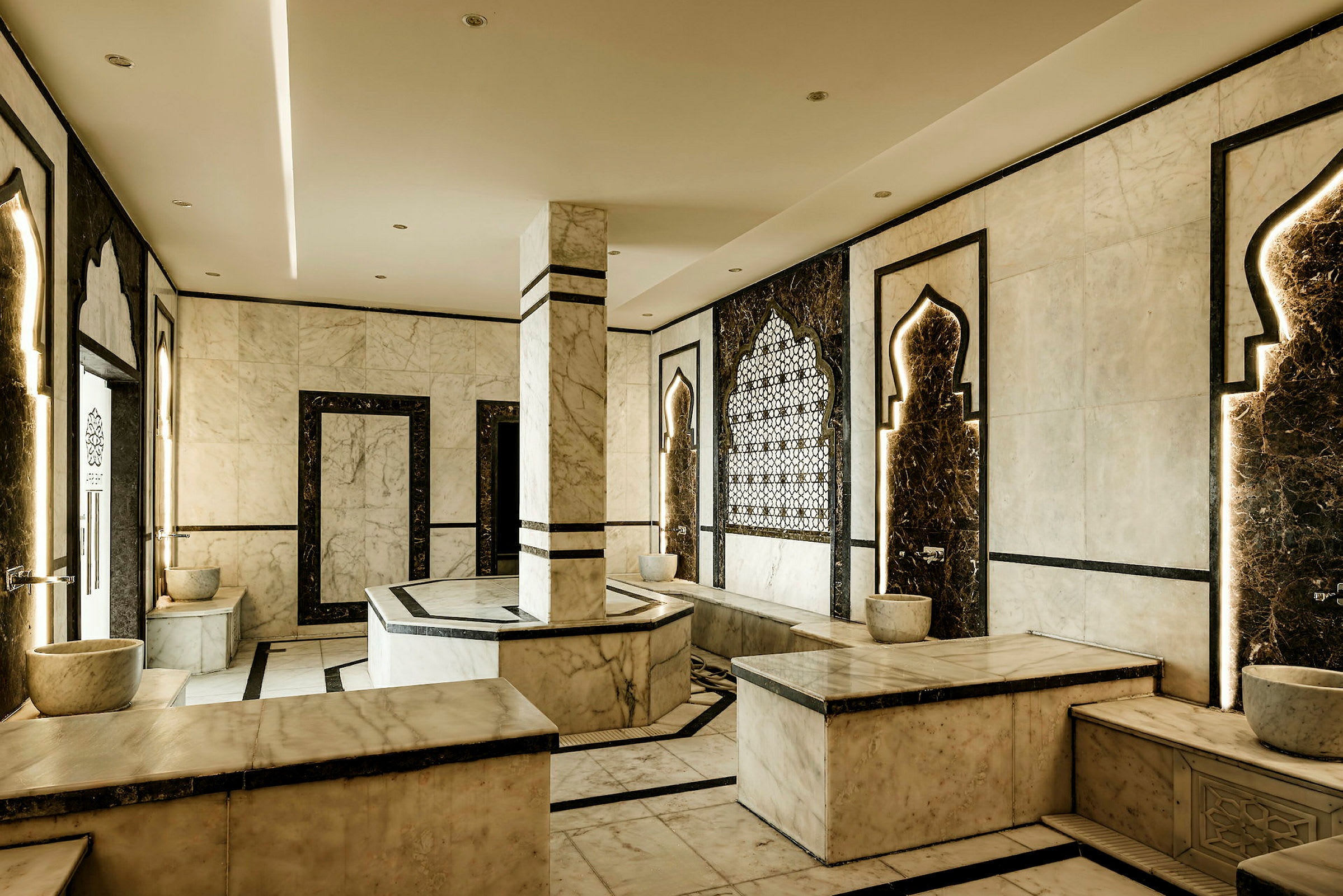Huone perinteisessä hamam-tyylissä, marmorisilla sisustuksilla, koristeellisilla kuvioilla ja penkkeillä. (Tekoälyn luoma teksti)
