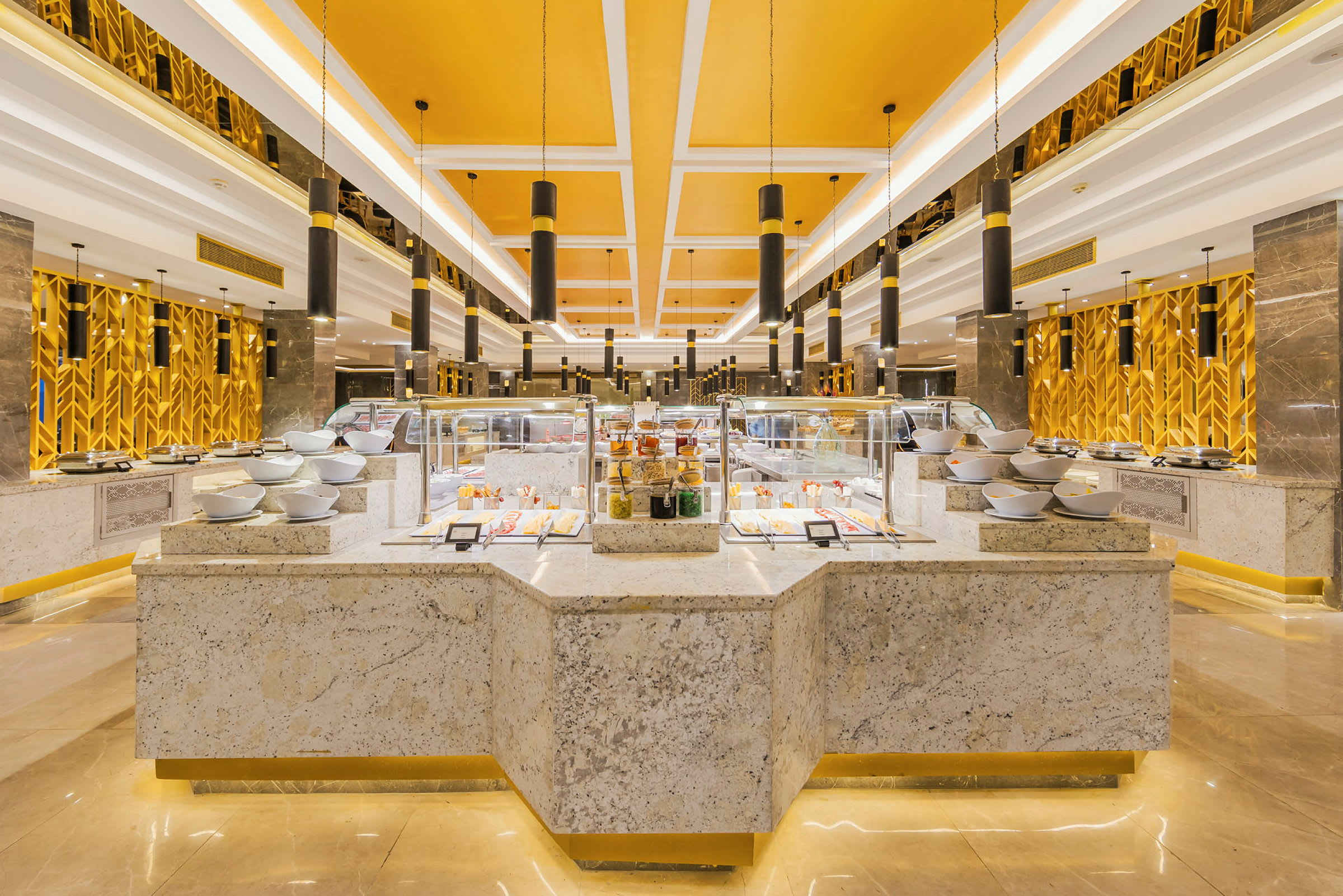 Buffet-alue, jossa on tarjoilutiskit ja kulhot sekä keltainen sisäkatto. (Tekoälyn luoma teksti)