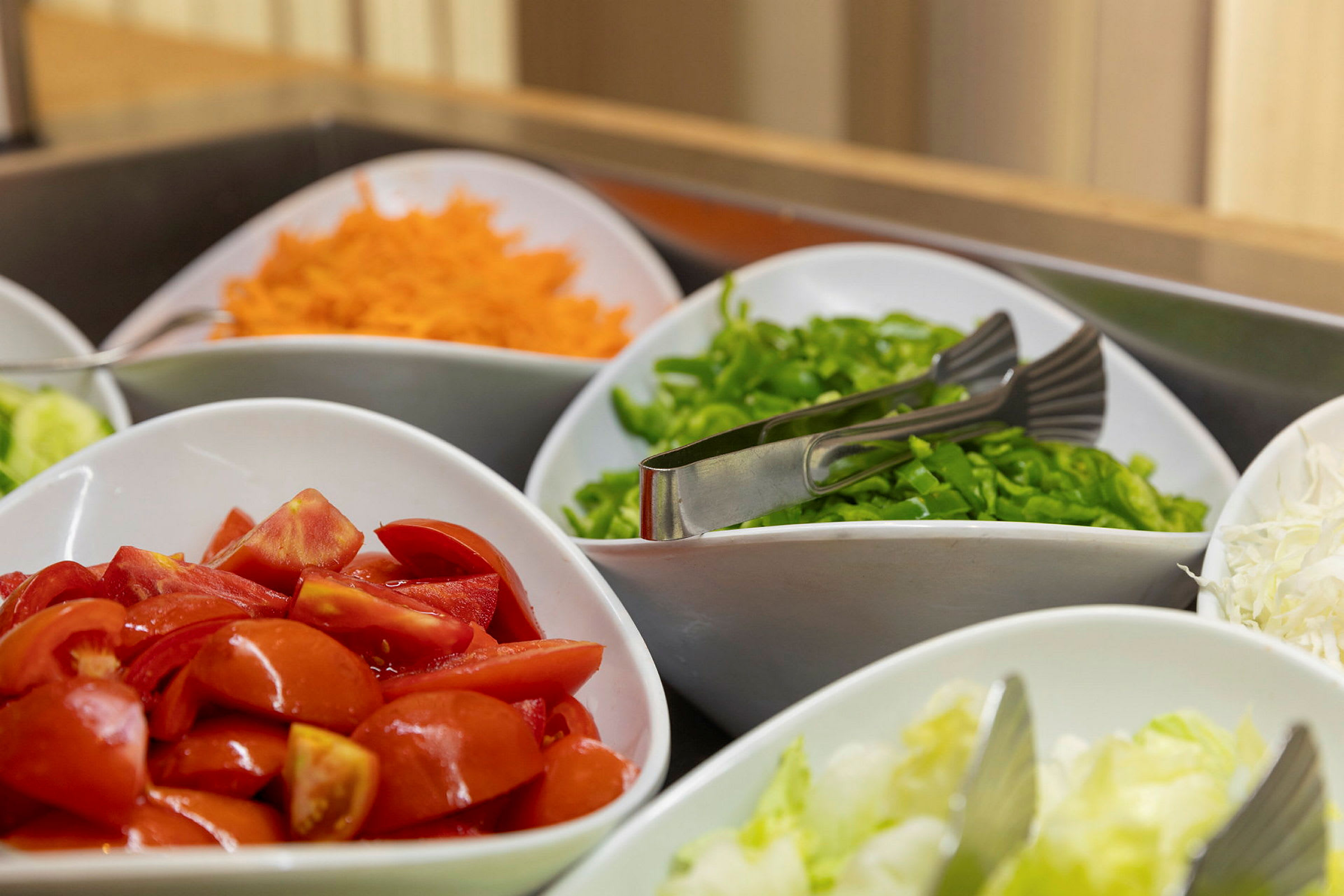Tuoreita vihanneksia aseteltu kulhoihin, mukaan lukien tomaatit, porkkanat ja paprika. (Tekoälyn luoma teksti)