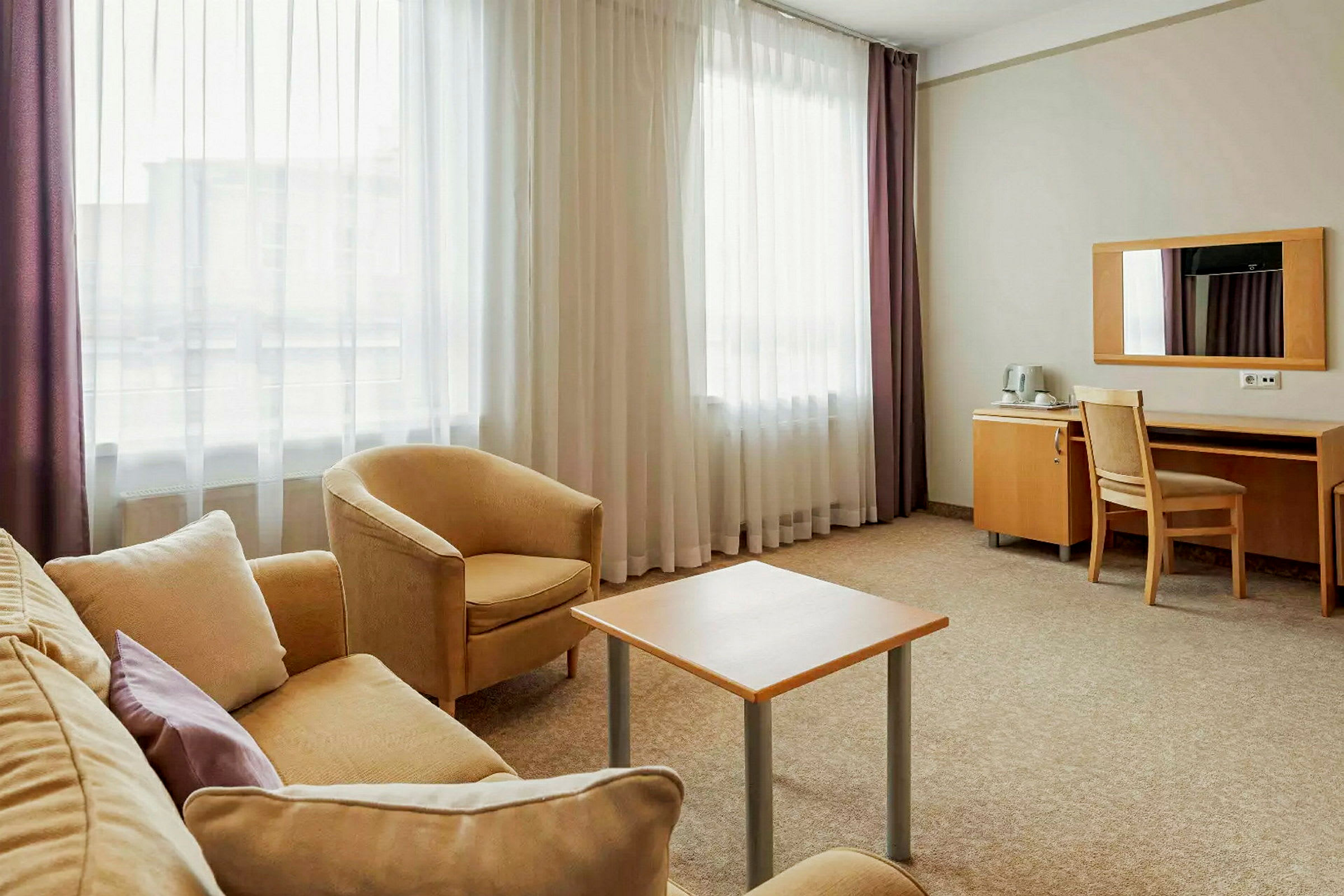 Hotellihuone, jossa istuinryhmä ja kirjoituspöytä. (Tekoälyn luoma teksti)
