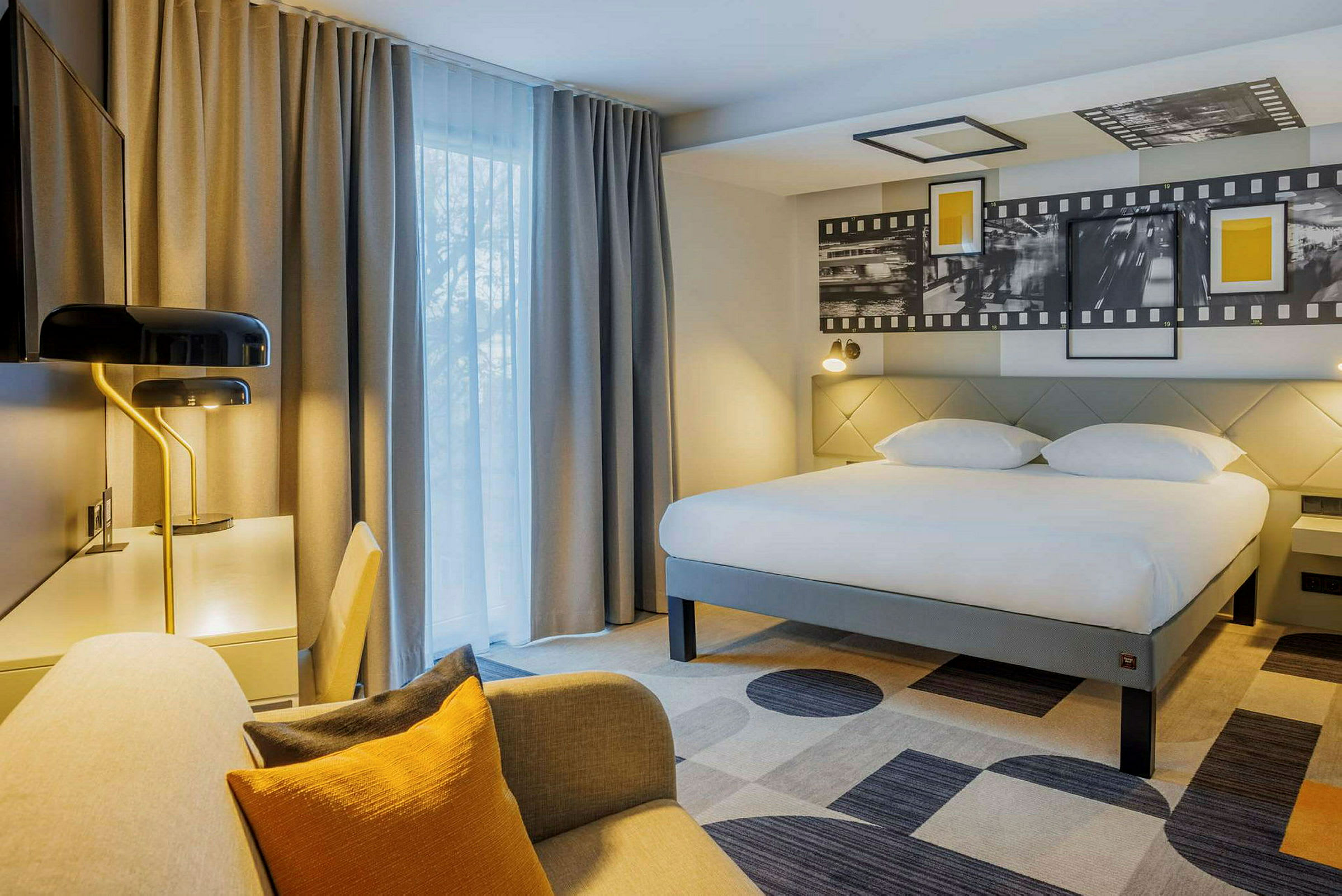 Hotellihuone, jossa suuri sänky, kirjoituspöytä ja istumapaikka. (Tekoälyn luoma teksti)